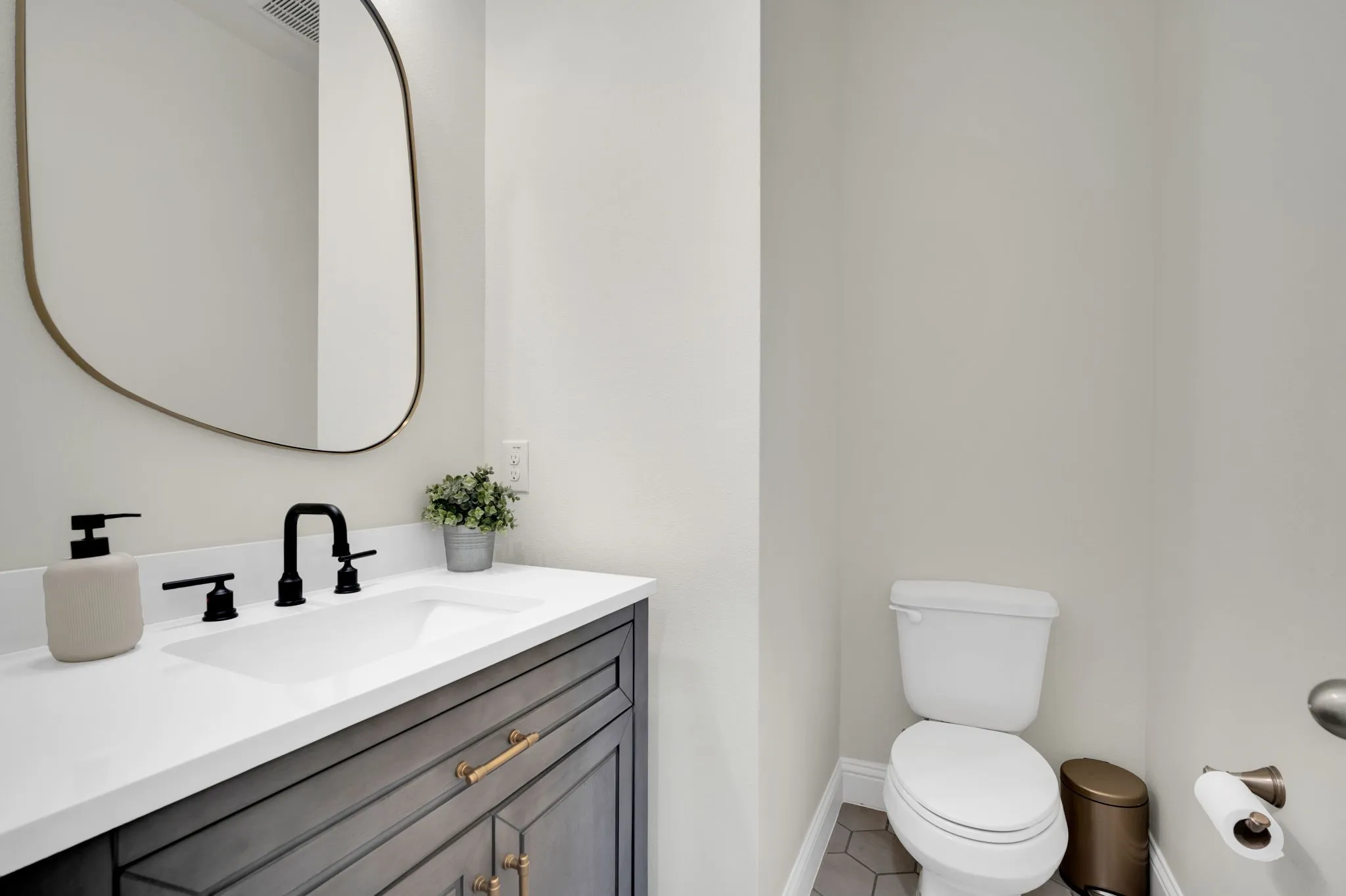 Vanity with white countertop and integrated sink, matte black faucet, and an oval mirror