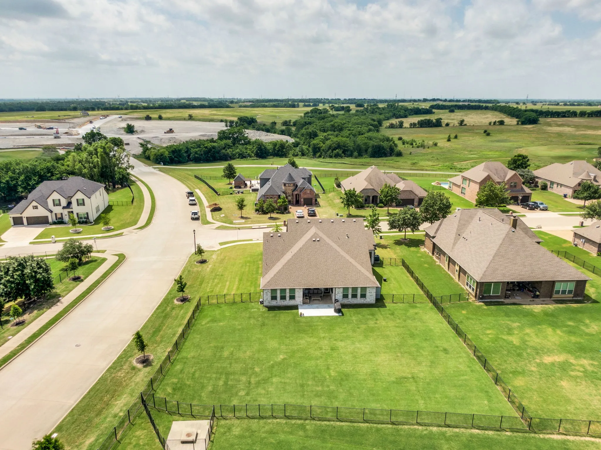 Spacious backyard featuring an expansive manicured lawn and black metal fencing