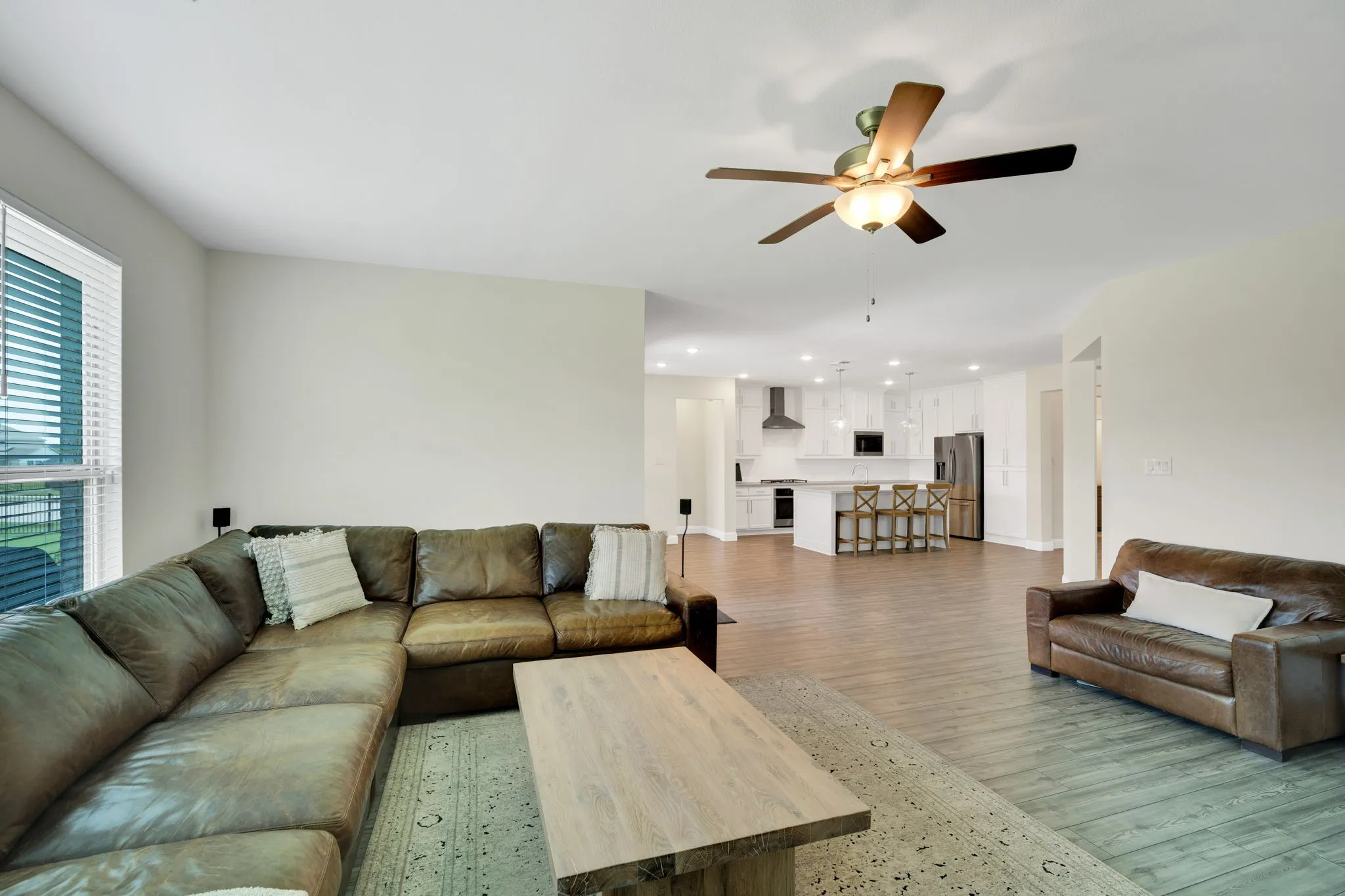 Open-concept living area featuring wood-finish flooring, a contemporary ceiling fan, and recessed lighting