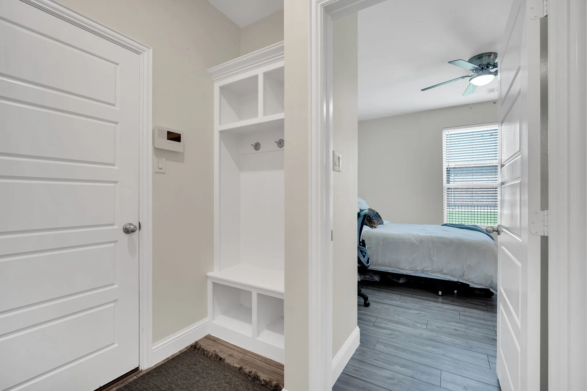 Entryway featuring built-in white cabinetry with cubbies and coat hooks, a contrasting dark wood-finish floor, and a white paneled door