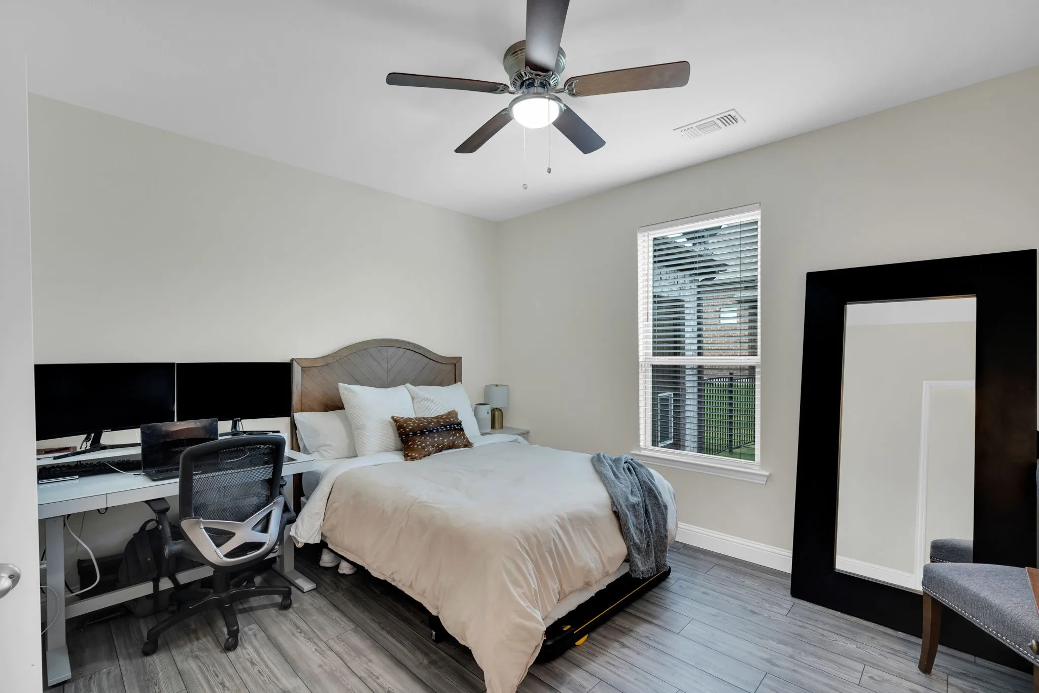 Room featuring light gray walls, wood-finish flooring, a ceiling fan with integrated lighting, and a single window with blinds