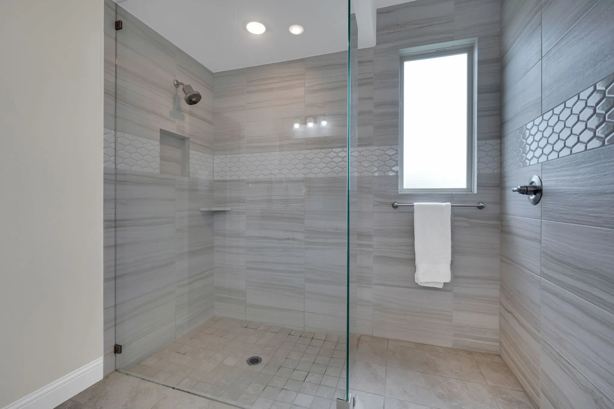 Spacious walk-in shower with clear glass enclosure and light-toned tilework