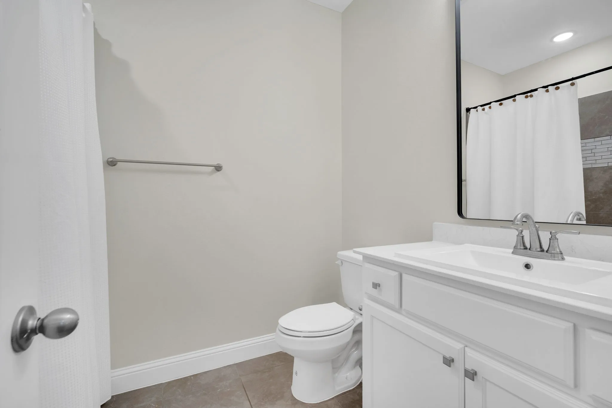 Bathroom featuring a white vanity with an integrated sink, polished chrome faucet, and a black-framed mirror
