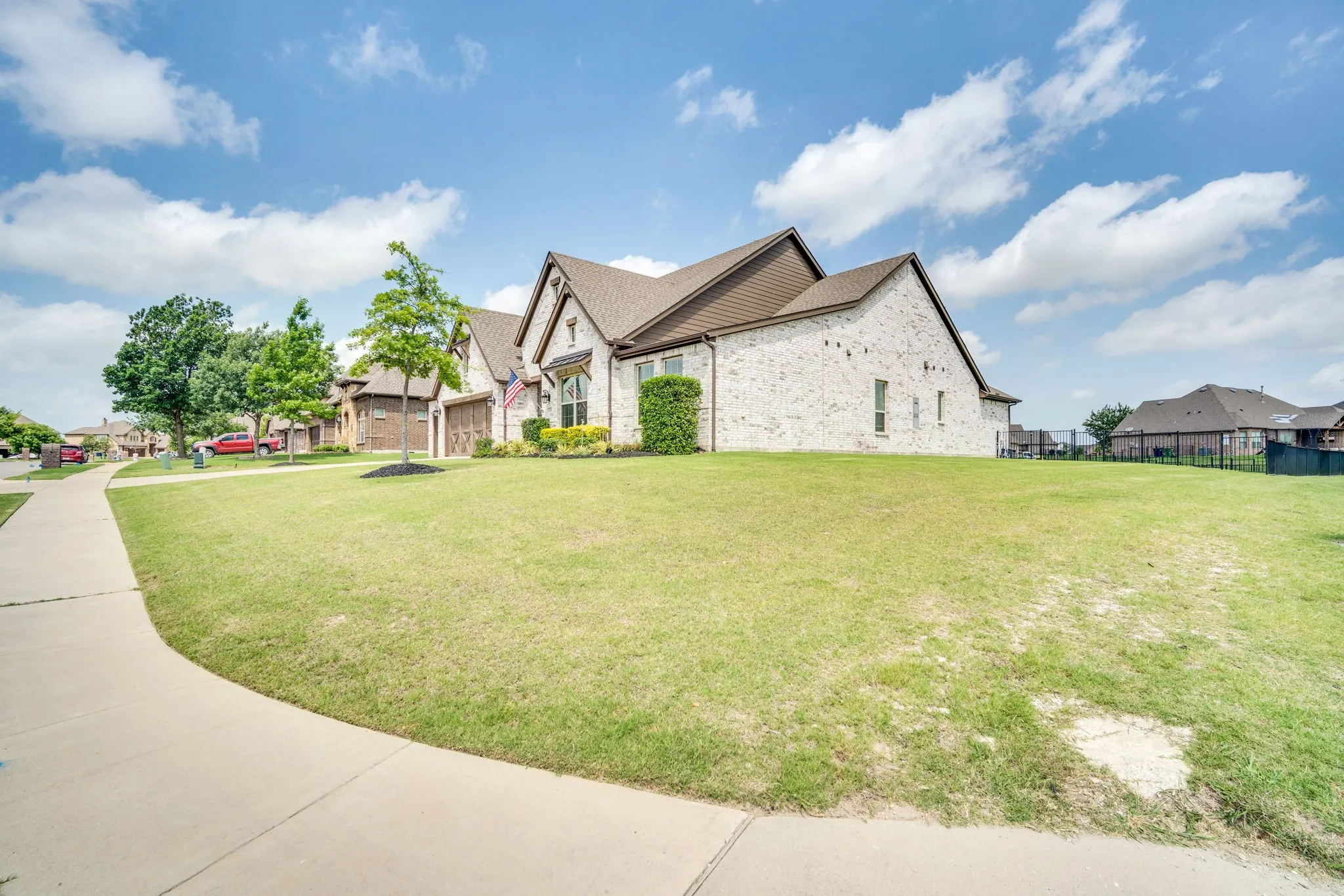 Expansive corner lot featuring a brick-clad home with a gabled roofline and attached garage