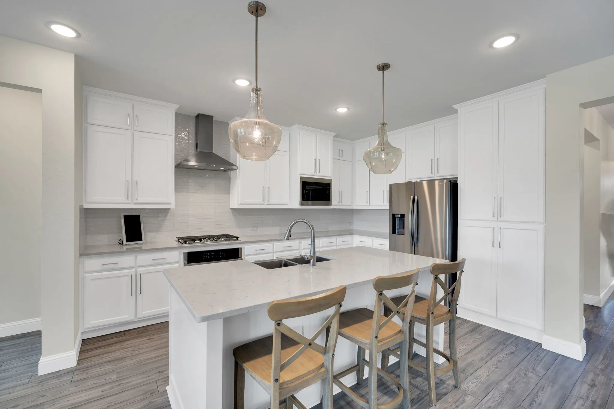 Modern kitchen featuring white shaker cabinetry, stainless steel appliances, a center island with counter seating, pendant lighting, and wood-finish flooring
