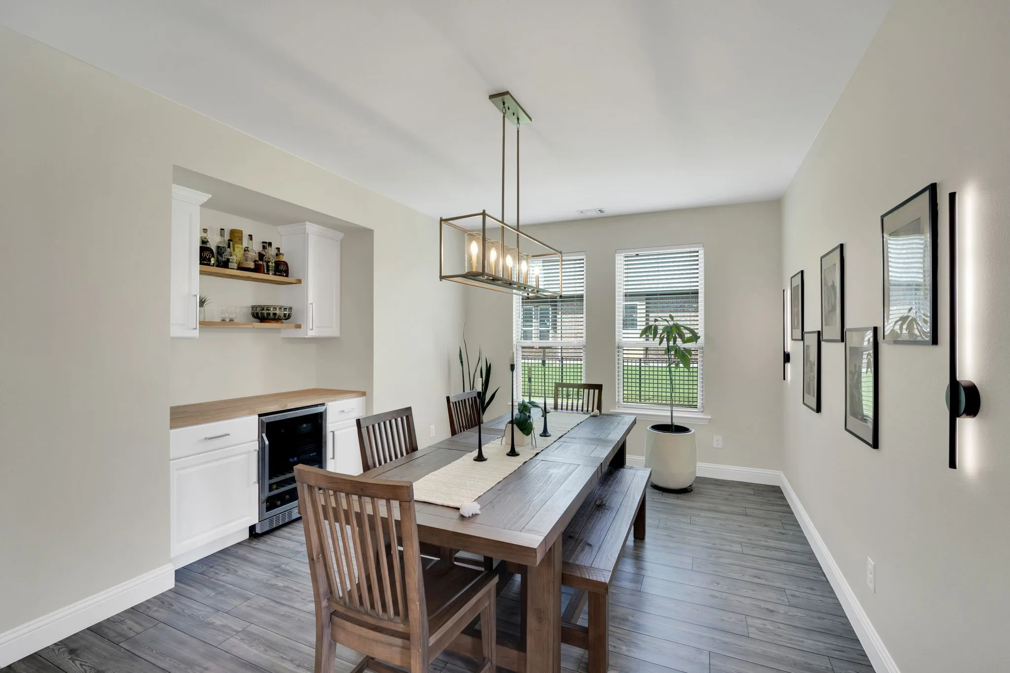 Dedicated dining area featuring wood-finish flooring, a built-in wet bar with white cabinetry, open shelving, and an integrated beverage refrigerator