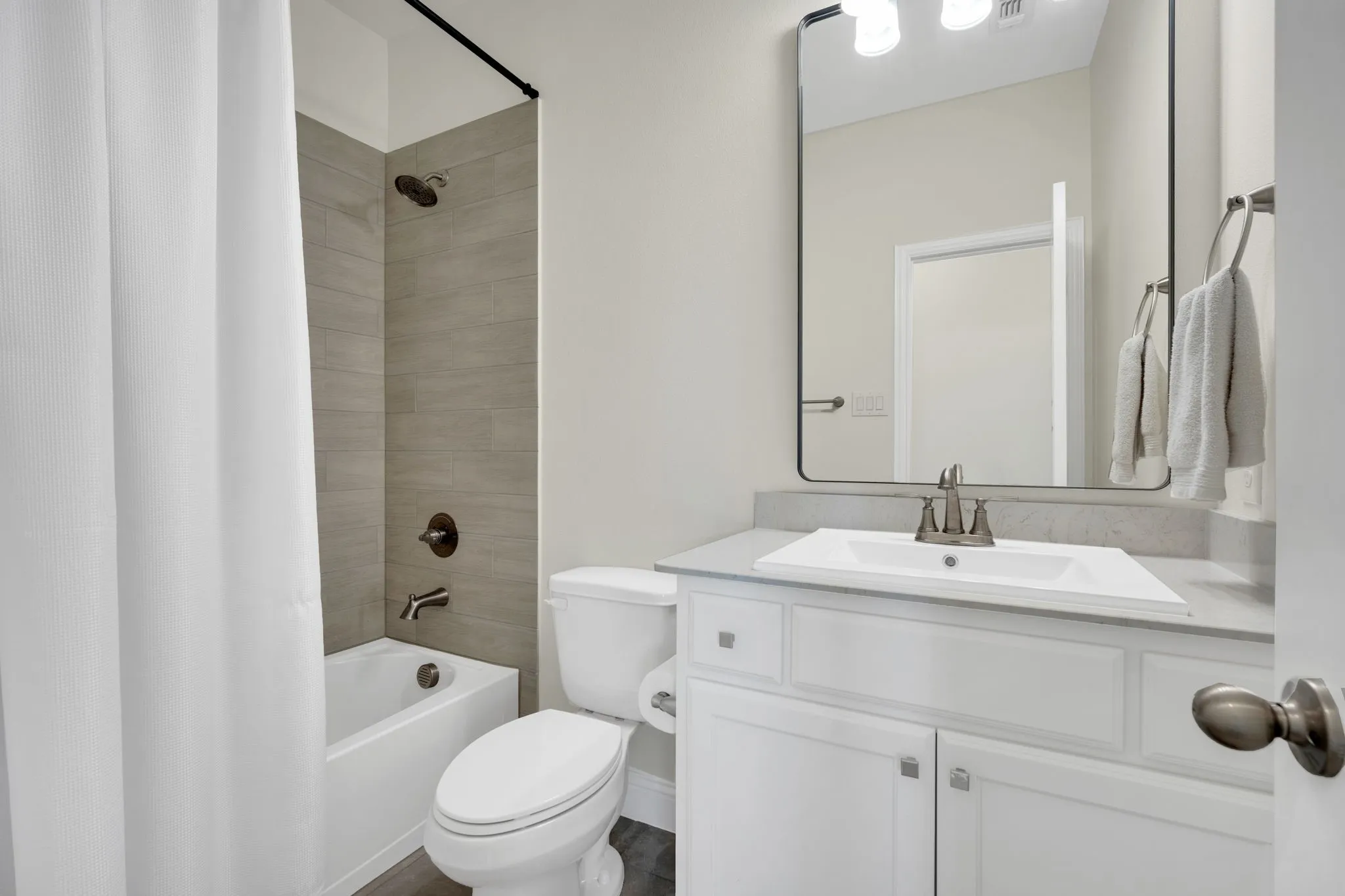Bathroom featuring a white vanity with a rectangular undermount sink, a light-toned countertop, and a framed mirror with integrated lighting