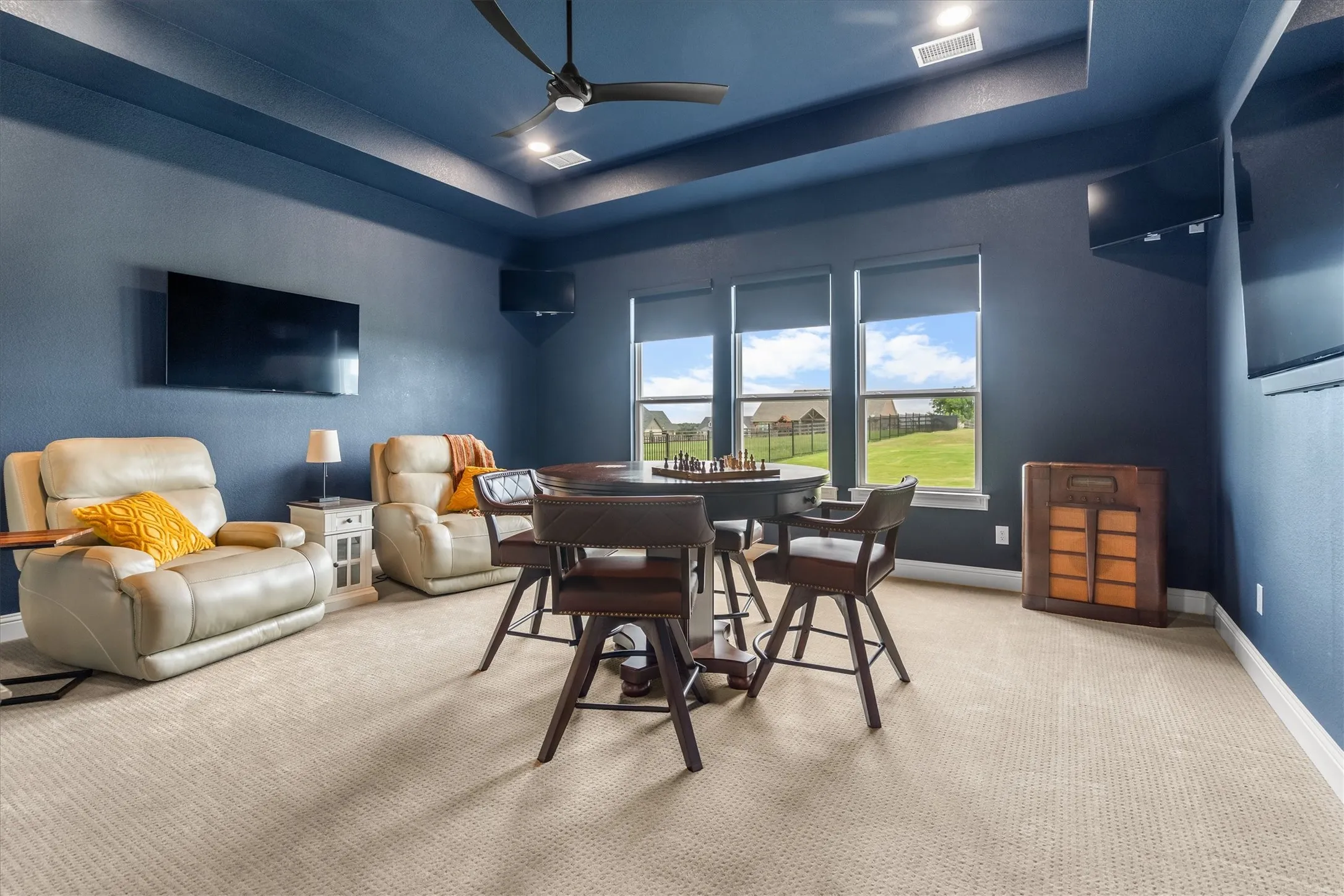 The huge game room at the back of the property has a media closet, electric black out shades, tray ceiling, and tvs at every angle! (The largest tv does not stay with the property, but the others do!)
