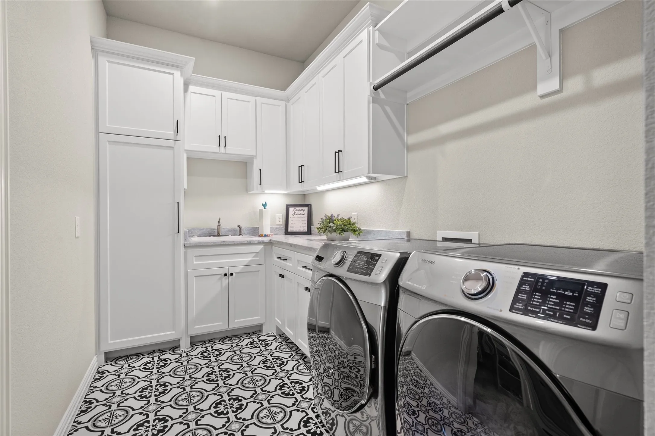 The laundry room with storage, counter and a sink can be accessed from the primary closet of the hallway.