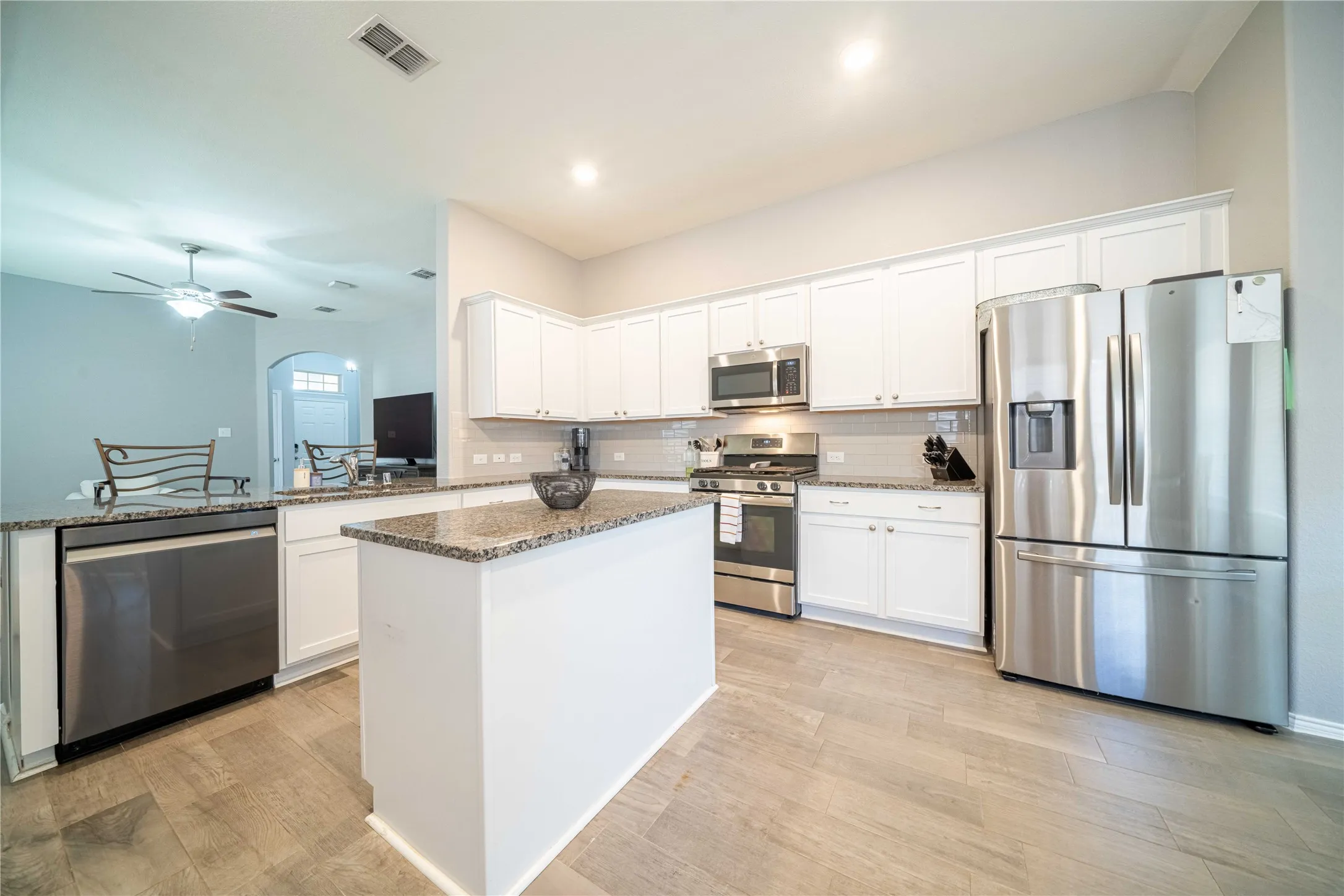 Kitchen featuring white cabinetry, ceiling fan, dark stone countertops, appliances with stainless steel finishes, and kitchen peninsula