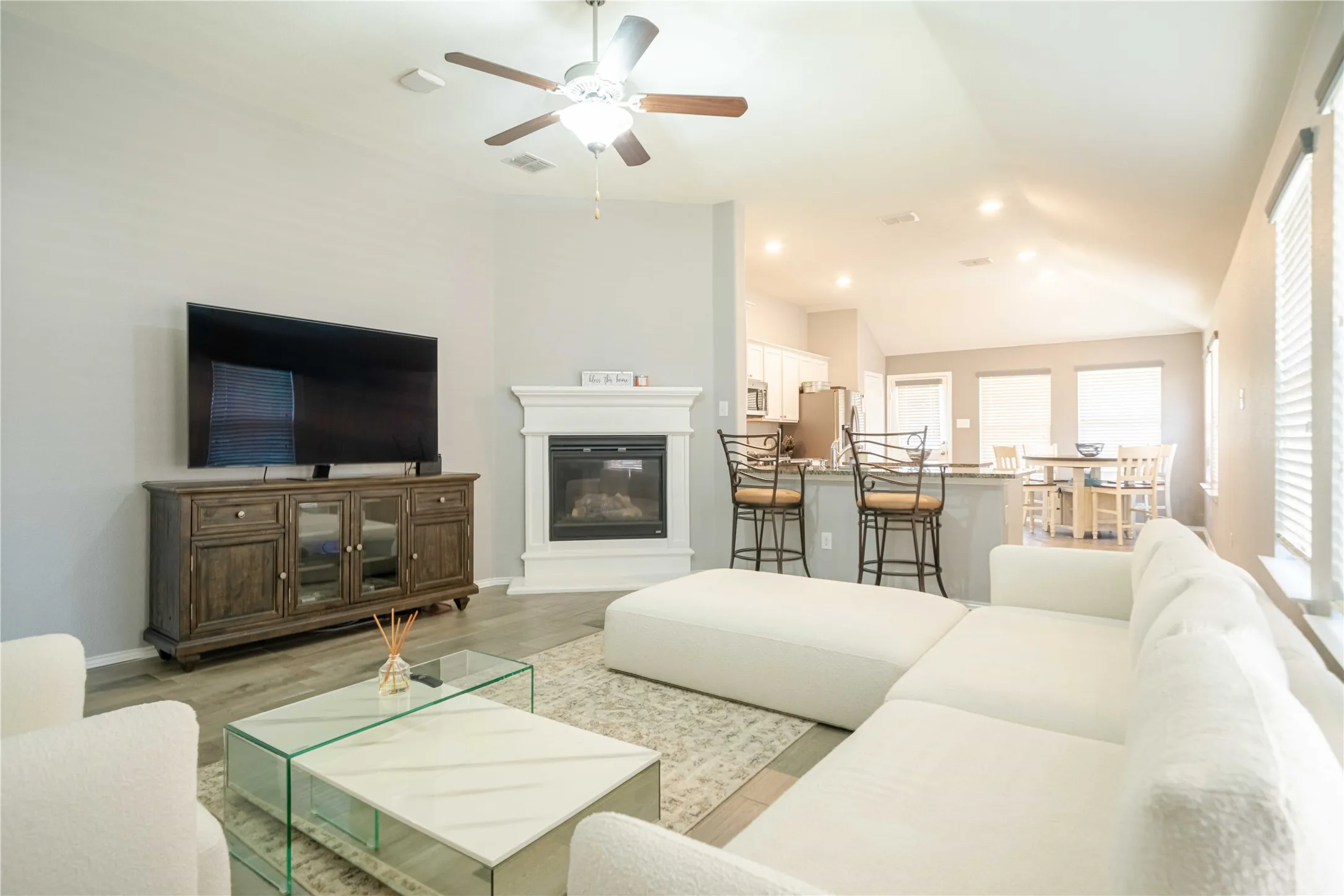 Living room with vaulted ceiling, light hardwood / wood-style flooring, and ceiling fan