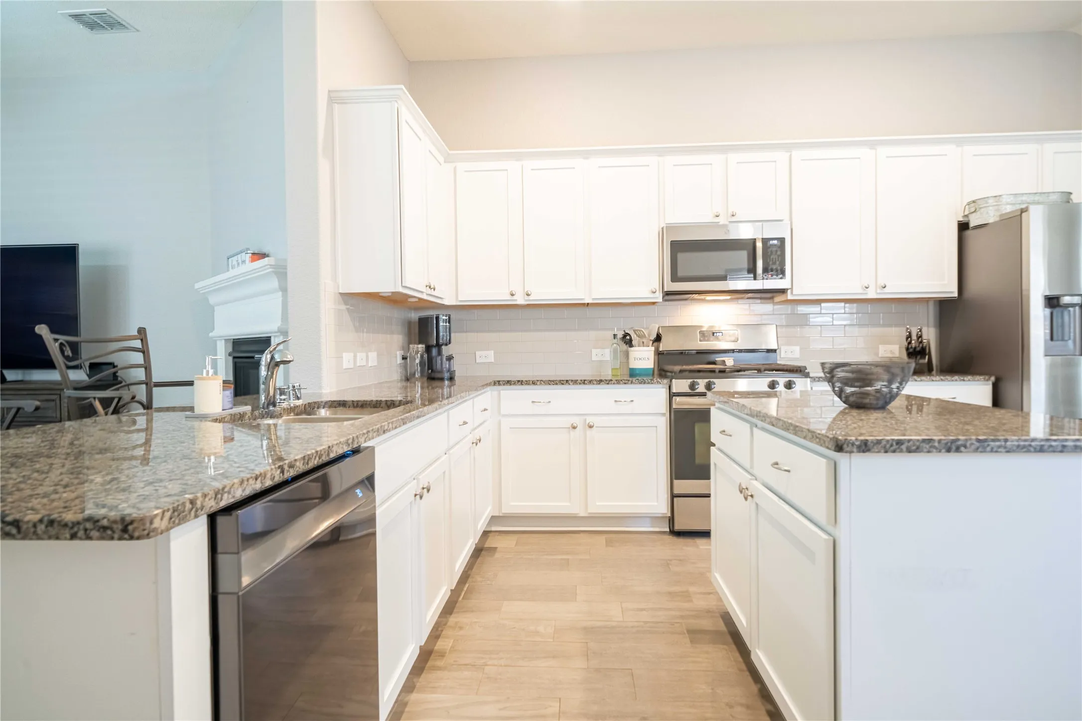 Kitchen featuring dark stone countertops, appliances with stainless steel finishes, white cabinets, and backsplash