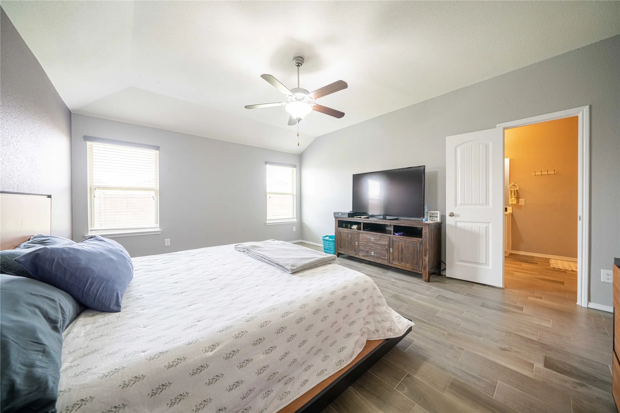 Bedroom with light hardwood / wood-style flooring, multiple windows, lofted ceiling, and ceiling fan