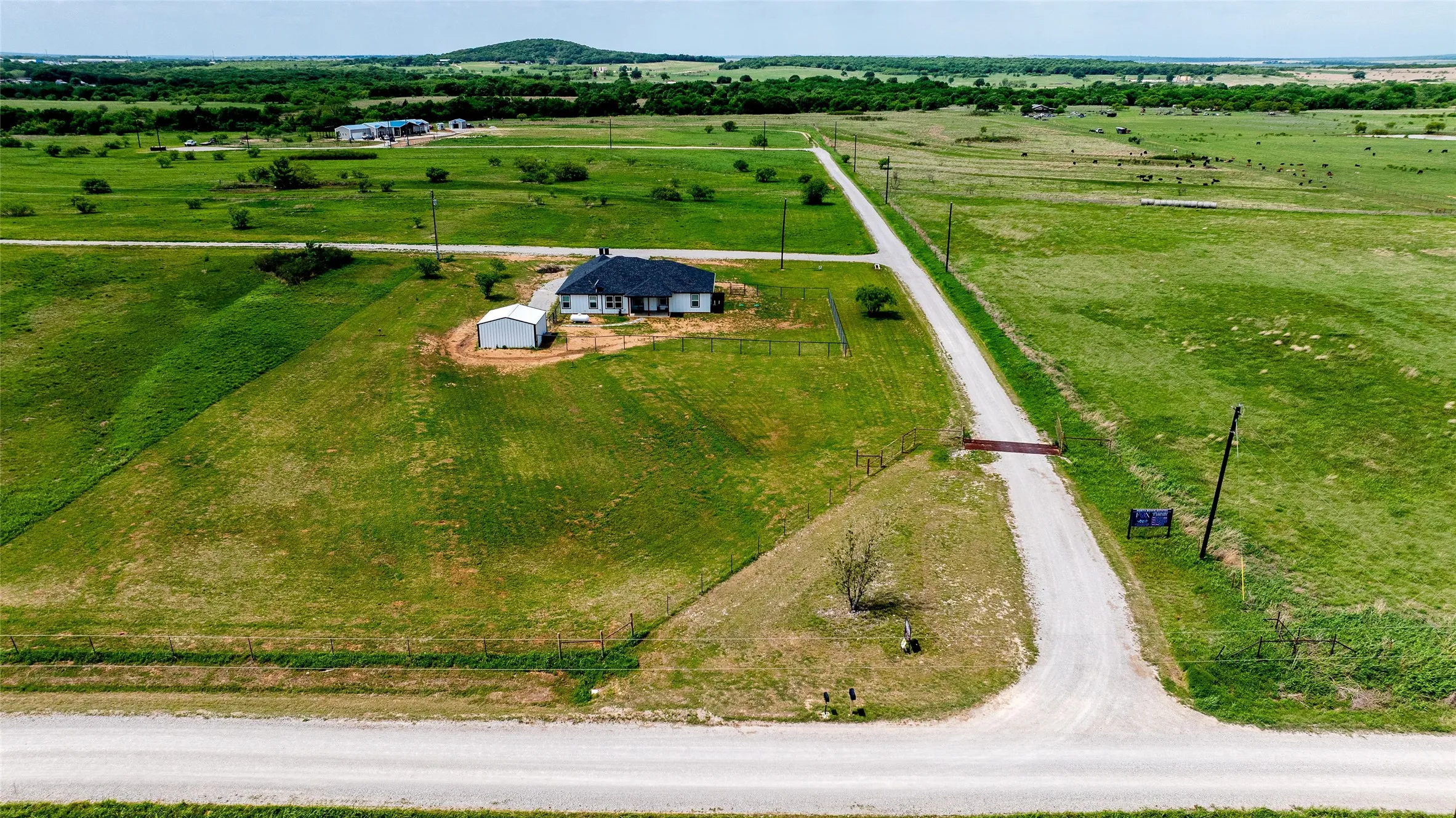 Expansive rural property featuring a single-story residence, a detached auxiliary building, and a long gravel driveway