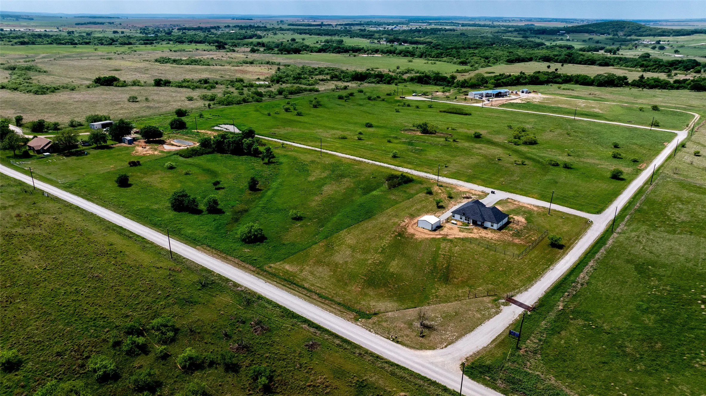 Expansive acreage featuring a single-story residence with a dark roof and light siding