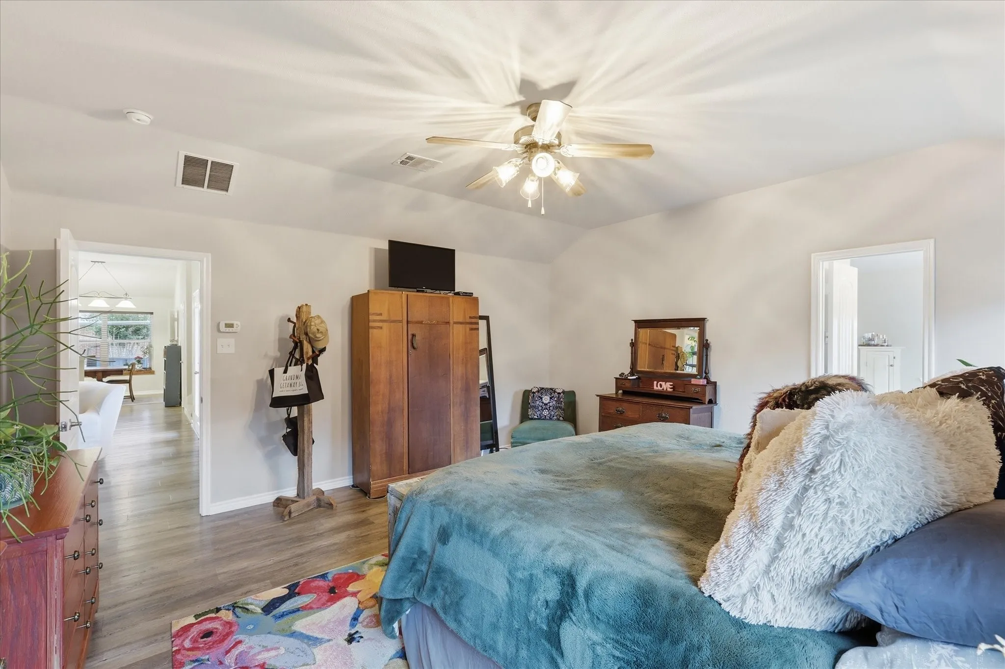 Primary bedroom featuring ensuite bath, hard floors and ceiling fan.