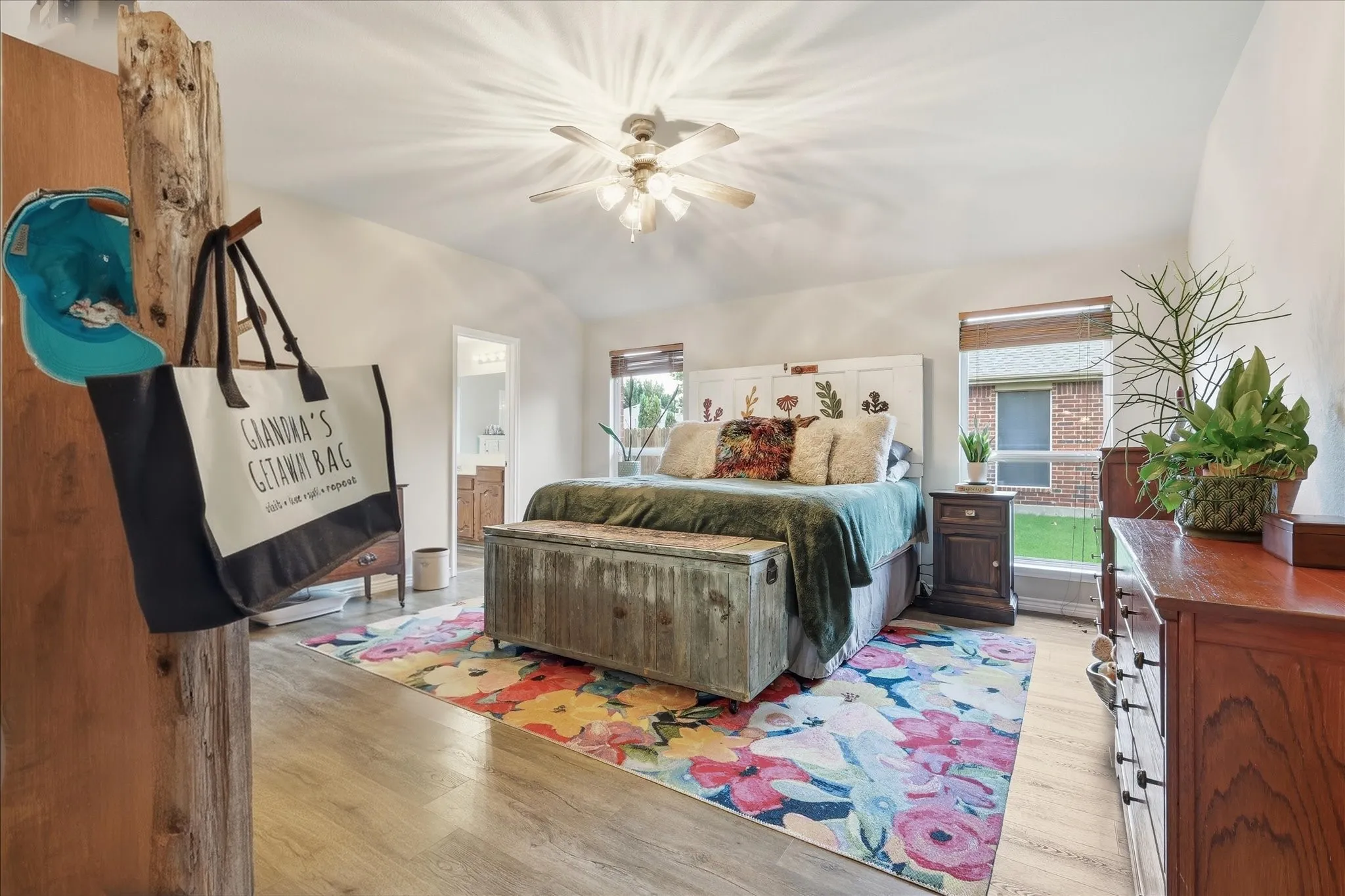 Primary bedroom featuring ensuite bath, hard floors and ceiling fan.