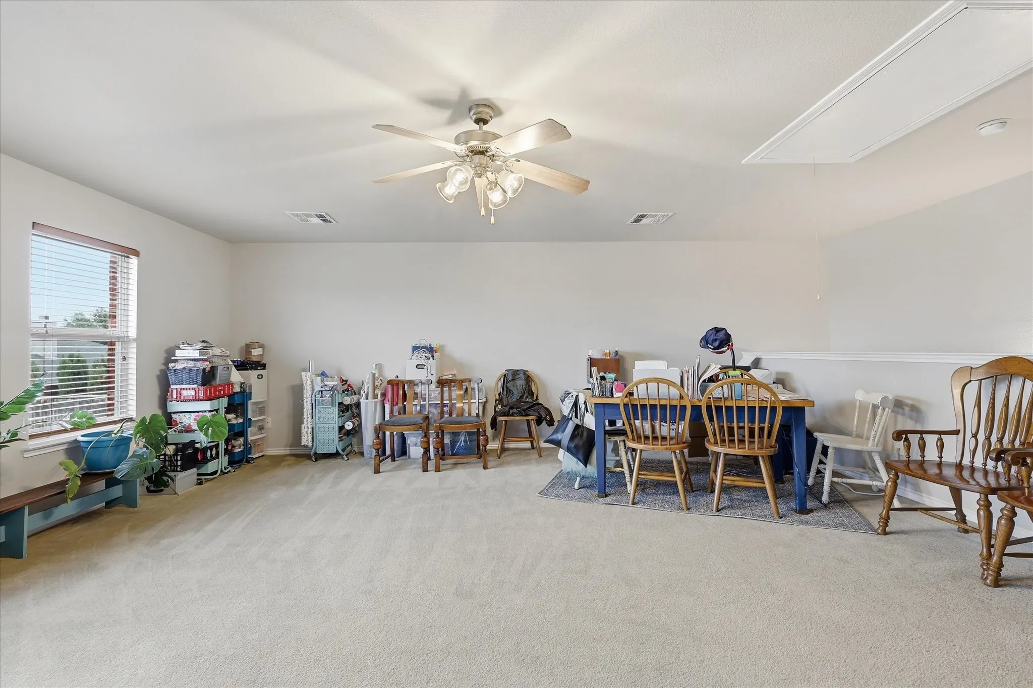 Upstairs Flex Room featuring windows at back of house, ceiling fan, attic entry.
