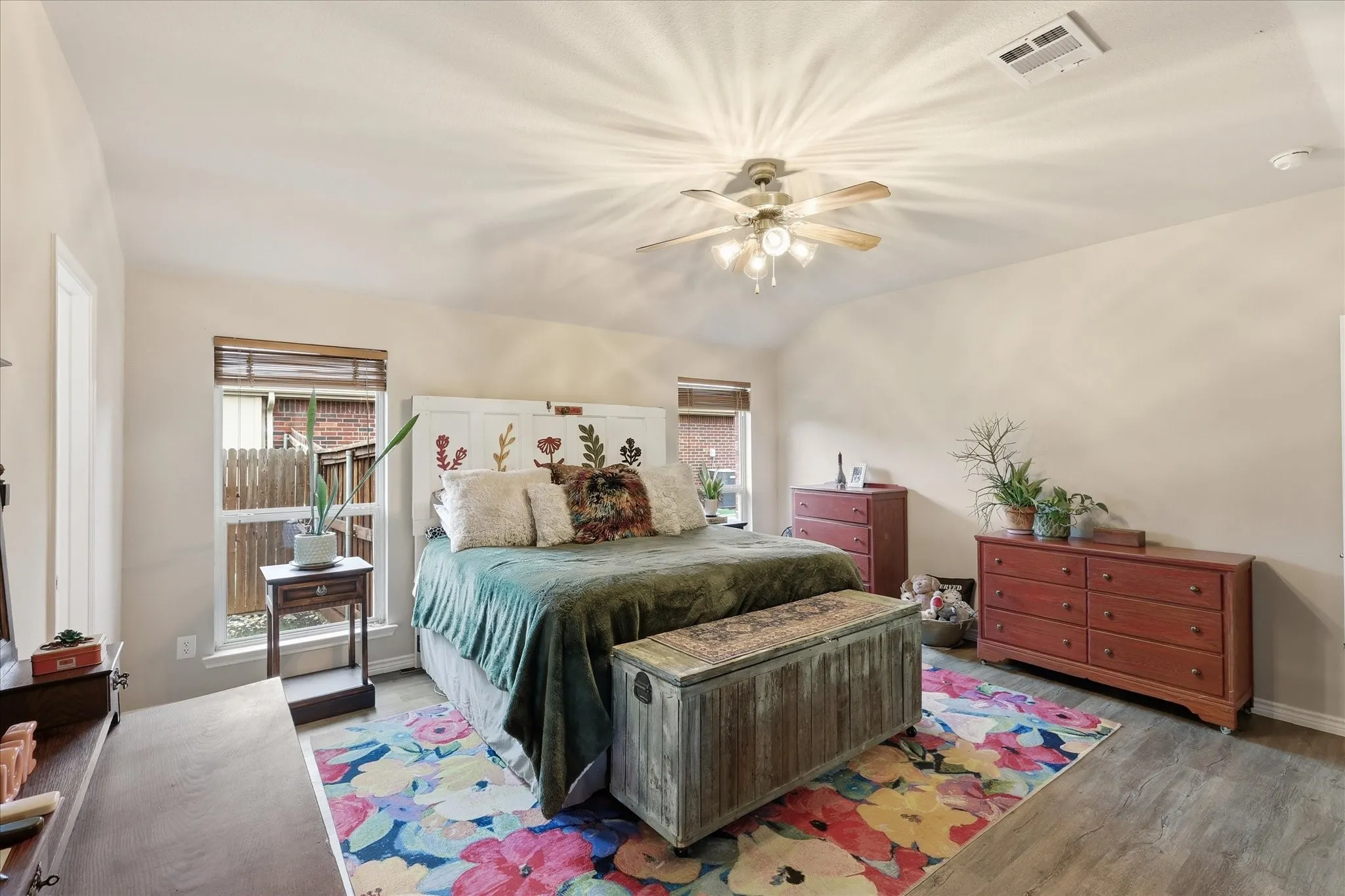 Primary bedroom featuring ensuite bath, hard floors and ceiling fan.