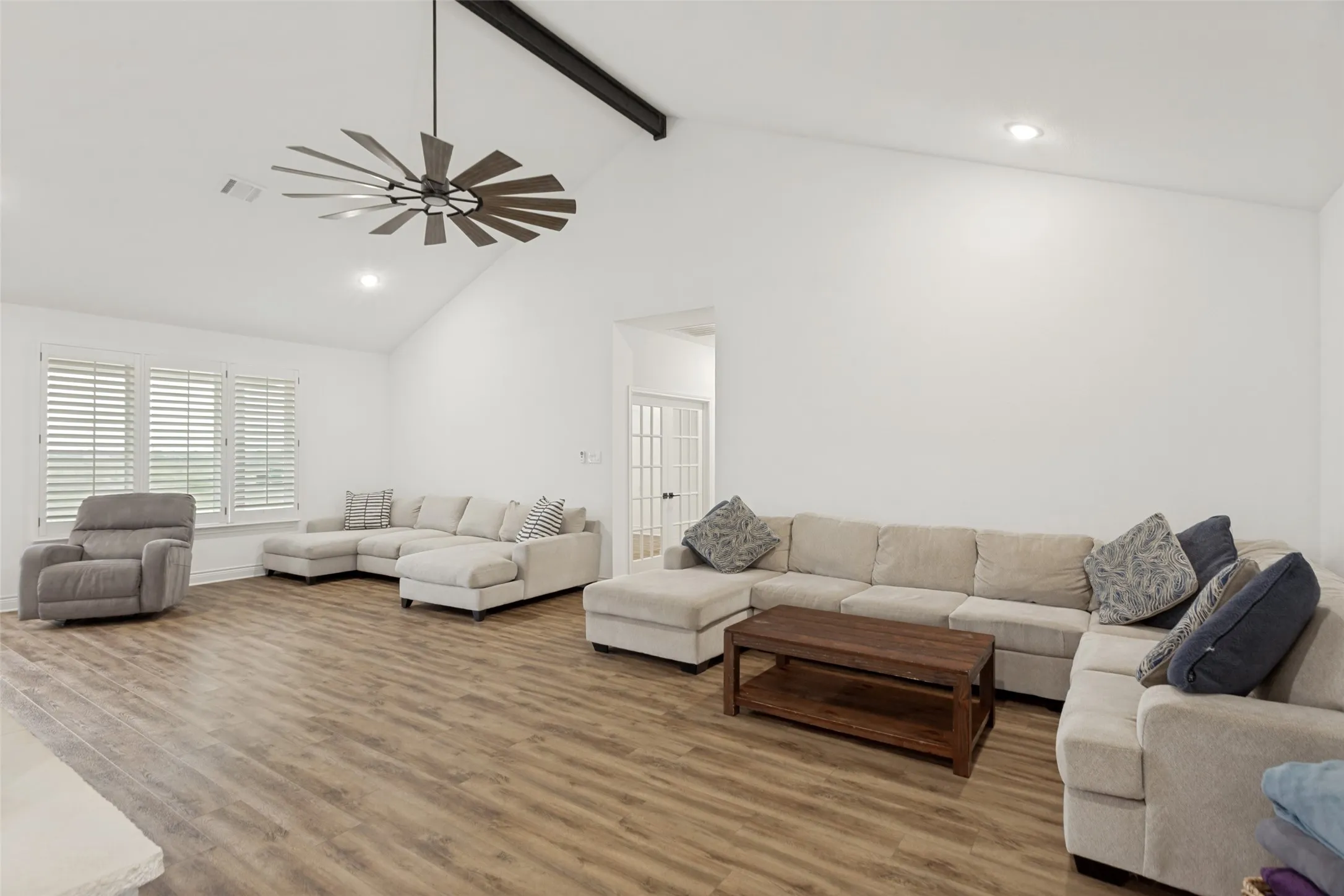 Spacious 30’ x 17’ living room with vaulted, beamed ceiling and attractive fan and fixture