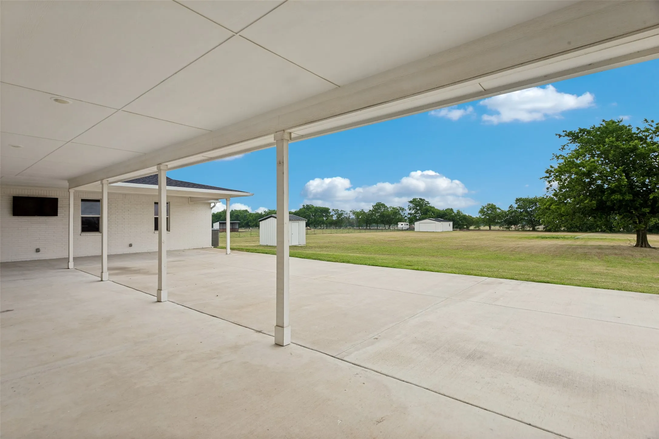 View of expansive L-shaped covered patio with extended concrete space for seating, entertaining, etc.