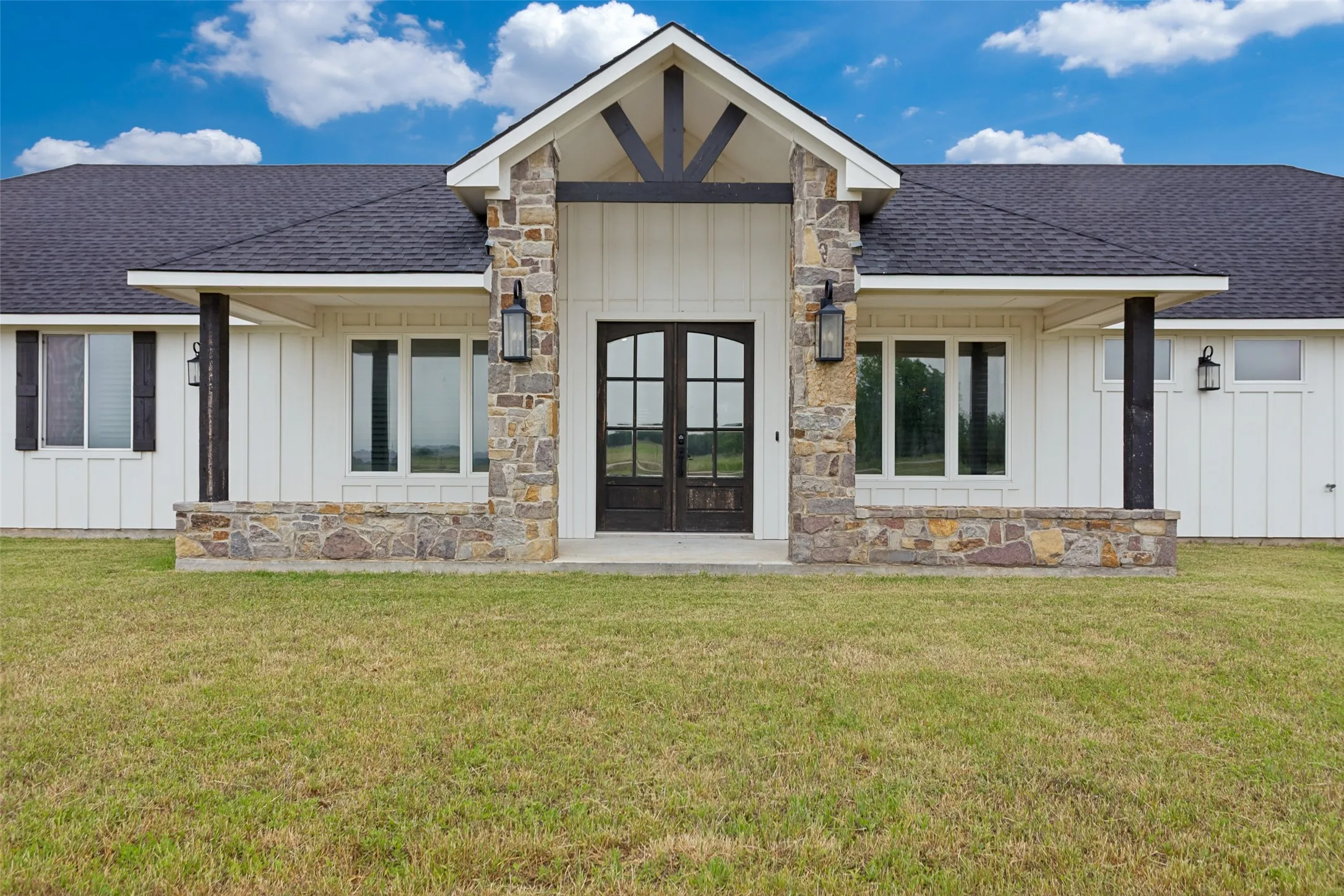 Welcoming front entry with double doors, covered front porch and attractive light fixtures
