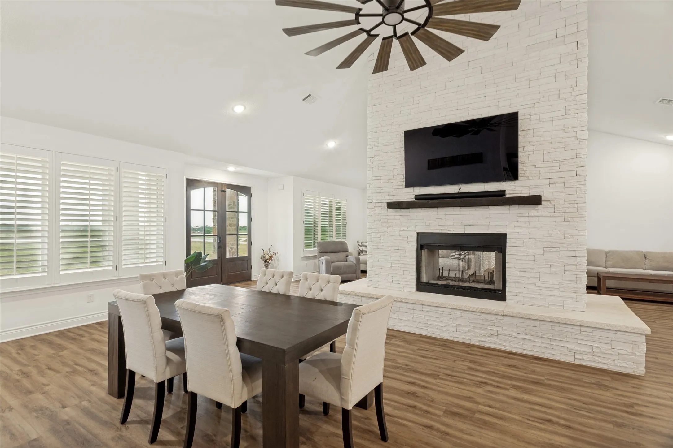 Spacious dining area with inviting fireplace, vaulted beamed ceiling and stately fan and fixture