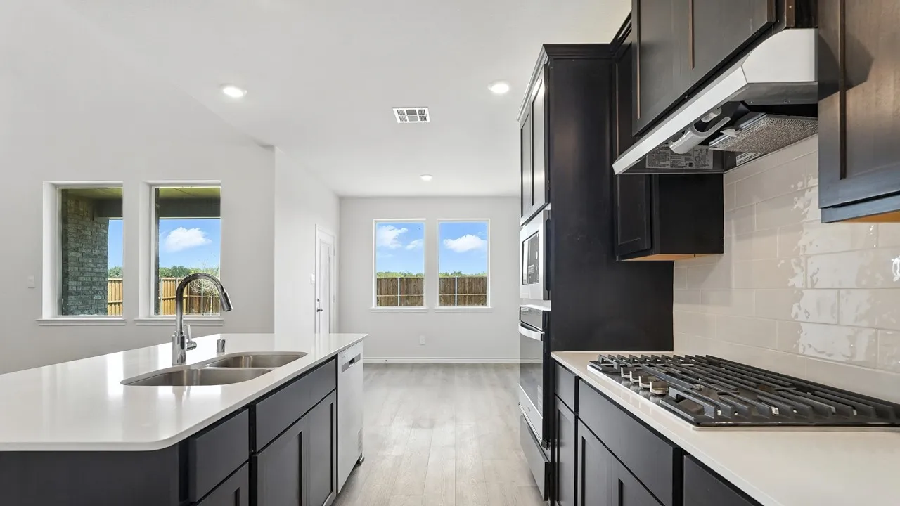Modern kitchen featuring dark cabinetry, light countertops, and an island with an integrated sink