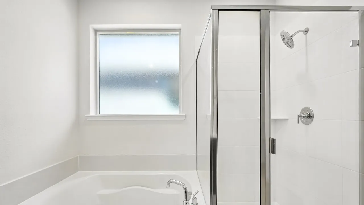 Soaking tub with a frosted window, paired with a glass-enclosed shower featuring white subway tile surround and chrome fixtures