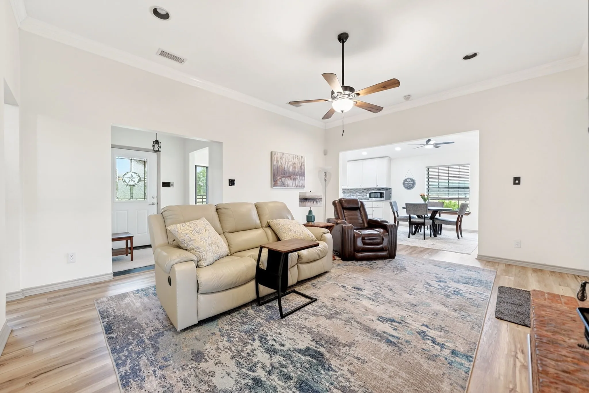 Spacious living area featuring wood-finish flooring, recessed lighting, and crown molding
