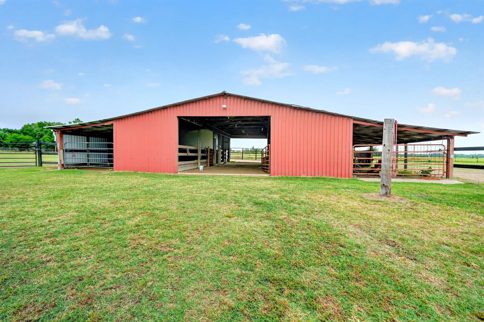 Red metal barn with an open-sided lean-to structure