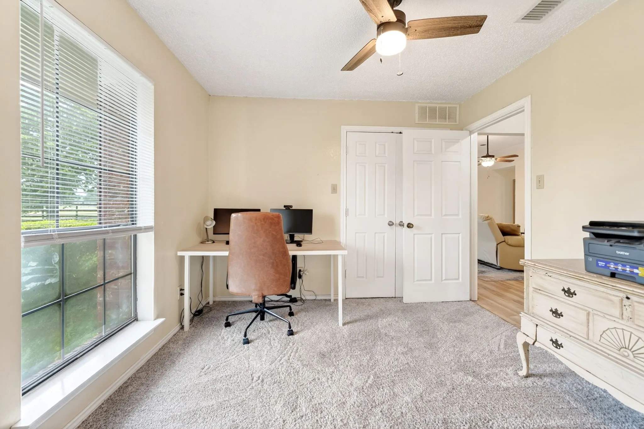 Carpeted room with a large window, a wood-finish ceiling fan, and double-door closet