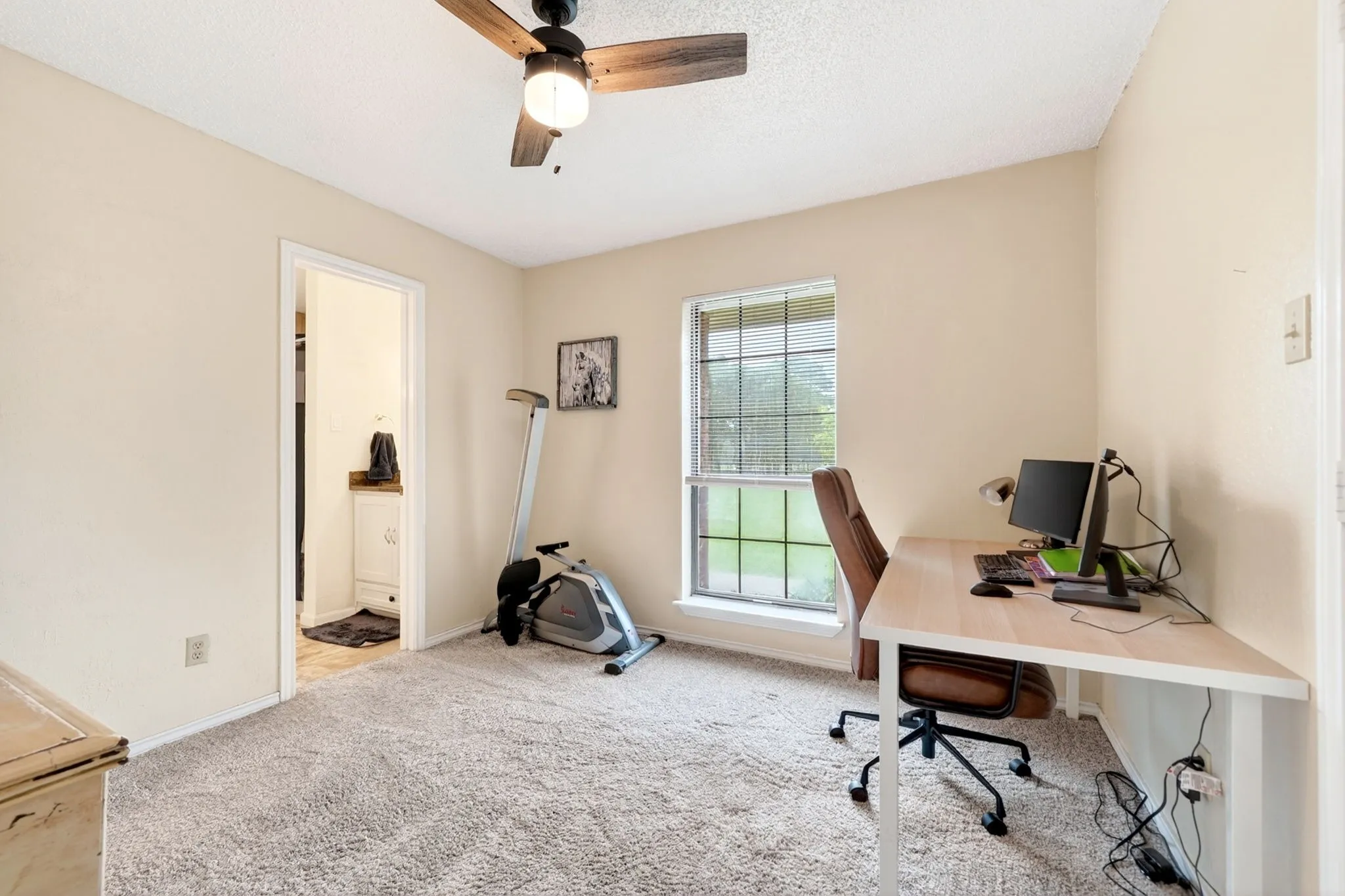 Carpeted room with a ceiling fan, a window, and a doorway leading to a vanity
