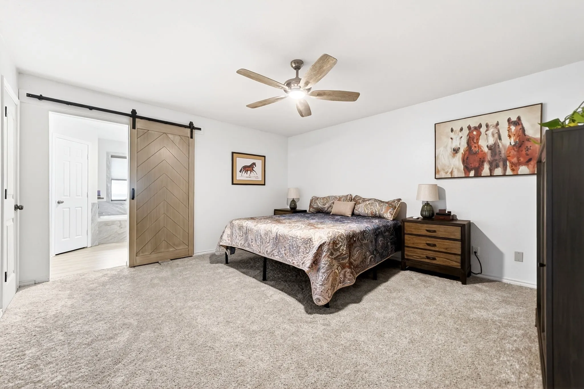Spacious bedroom featuring light-toned carpeting and a ceiling fan