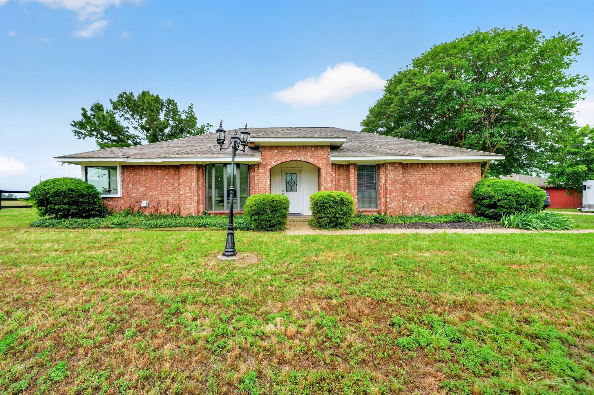 Traditional brick home featuring a prominent arched entry, a white paneled front door, and a multi-paned sidelight