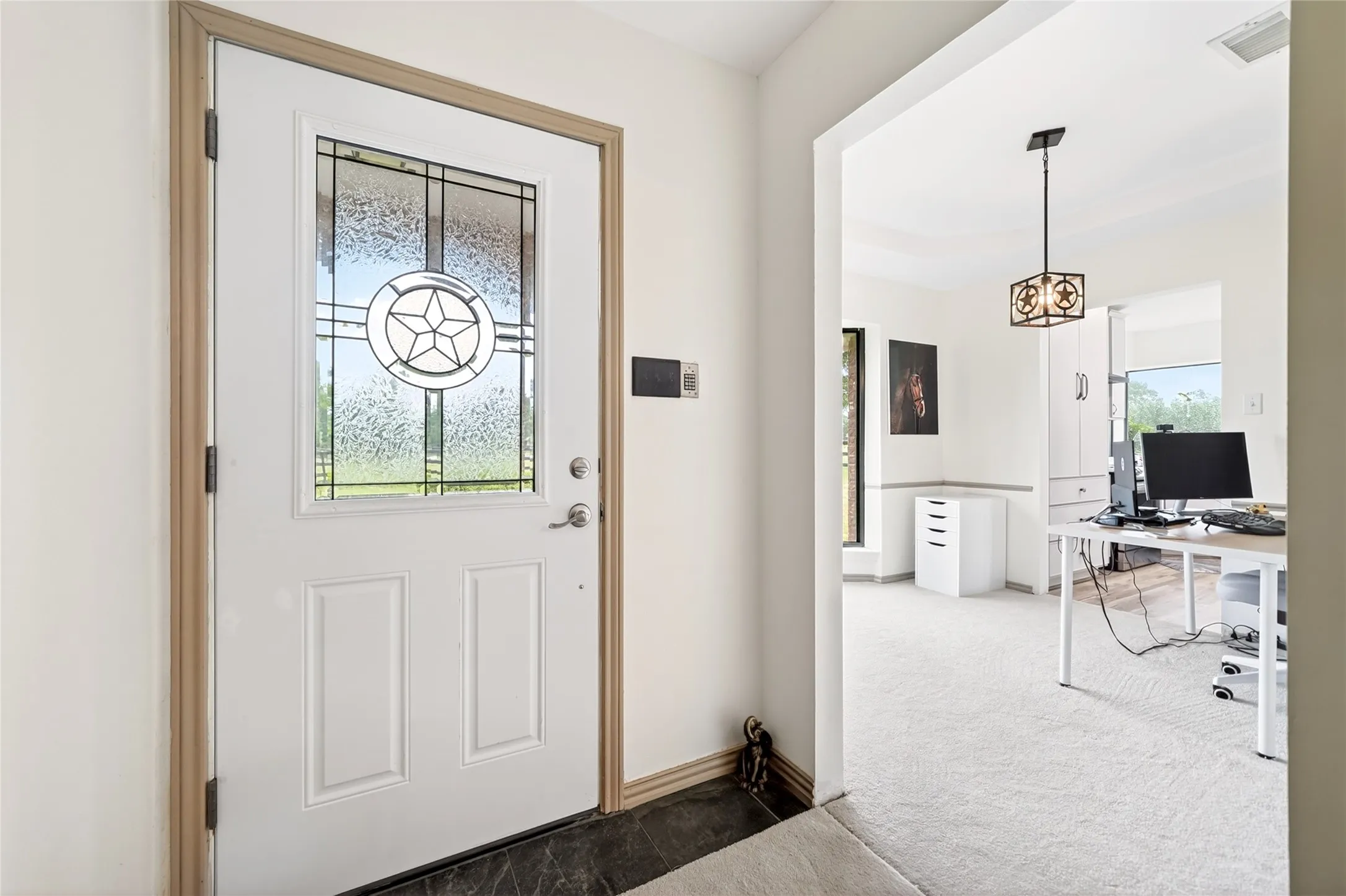 Entrance featuring a white paneled door with decorative glass inlay, dark flooring, and light wall finishes