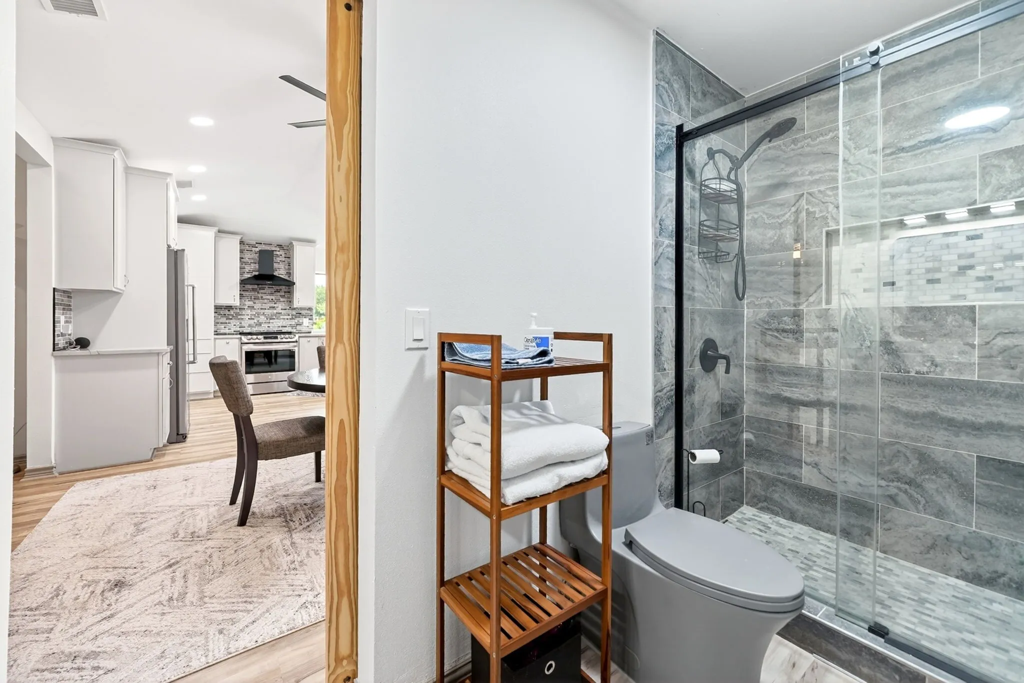 Modern bathroom featuring a glass-enclosed shower with large format grey stone-look tile, a recessed niche with mosaic accent tile, and matte black fixtures