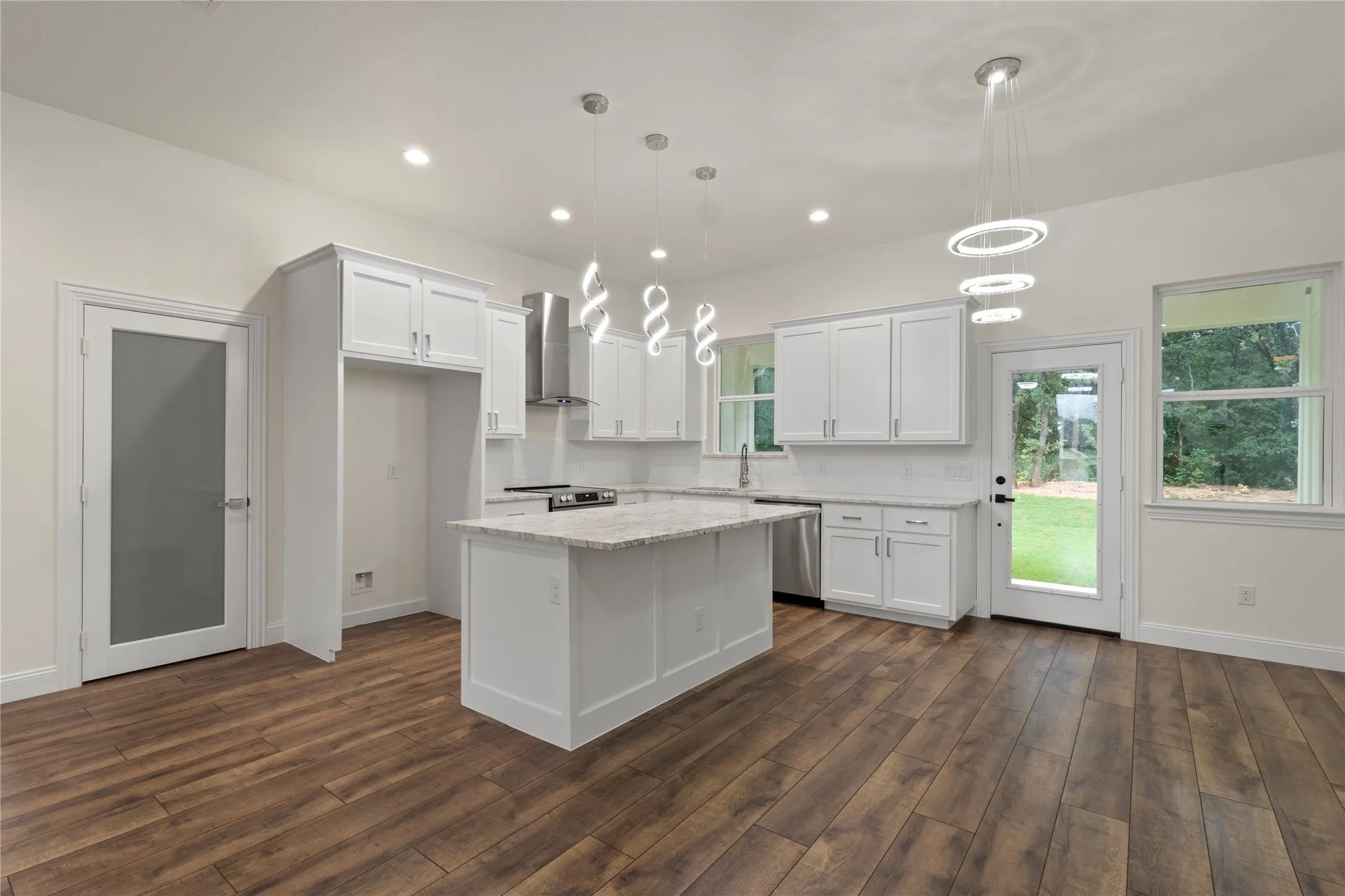 Spacious living area featuring wood-finish flooring, a modern ceiling fan, recessed lighting, and a contemporary fireplace with a wood mantle