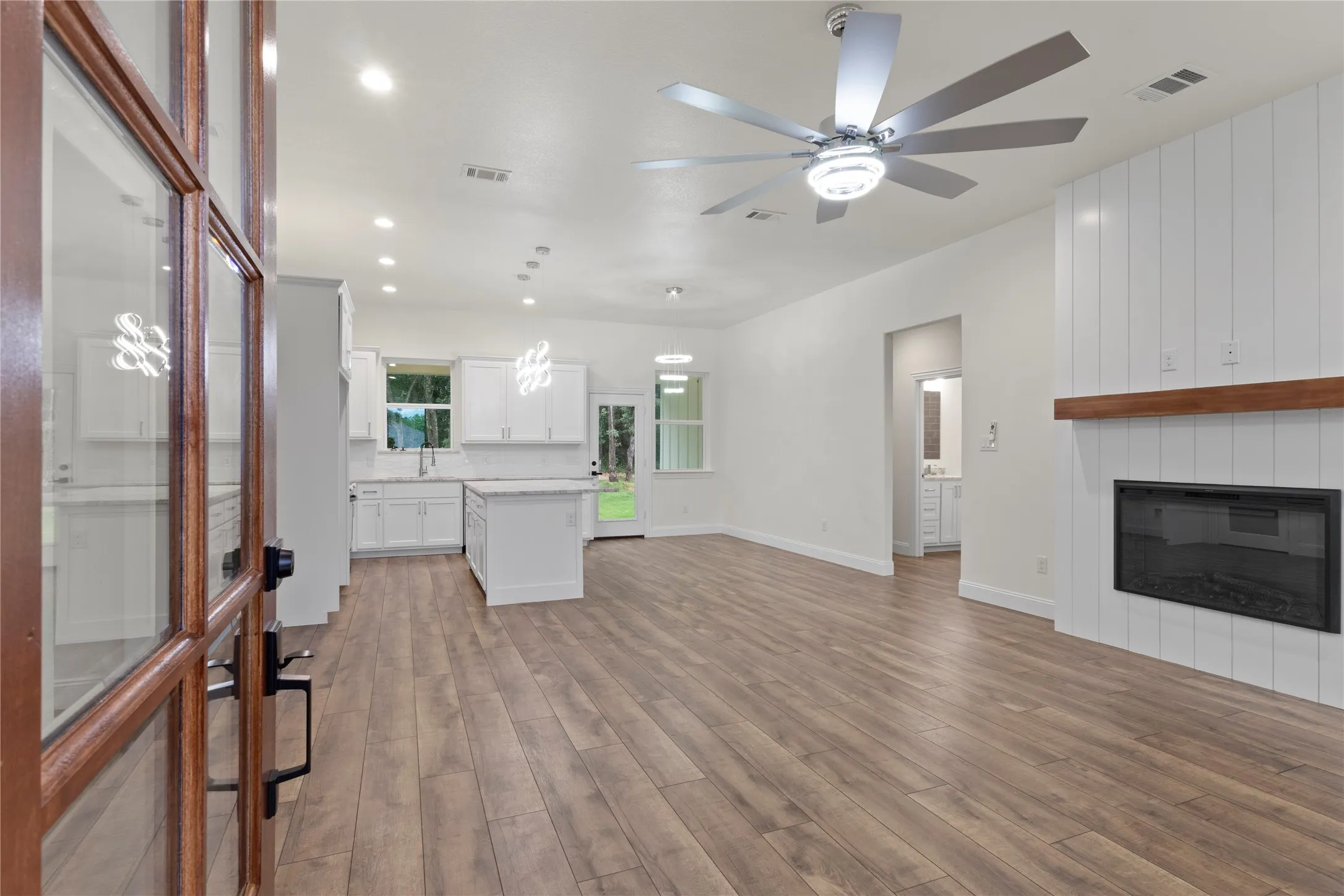 Open-concept interior featuring wood-finish flooring, a contemporary ceiling fan, and recessed lighting