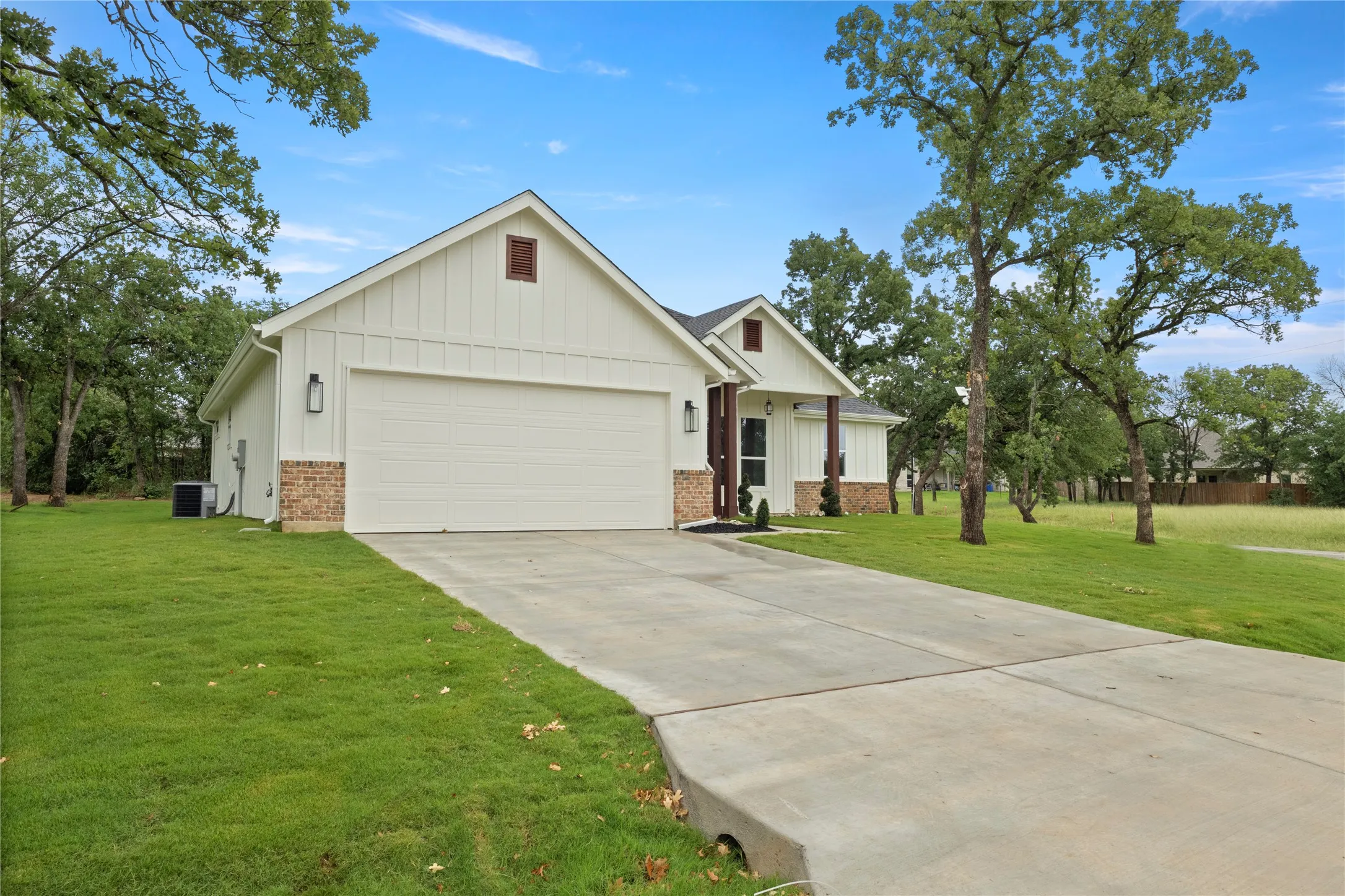 Contemporary white board-and-batten exterior with a two-car garage, brick accents, and a concrete driveway