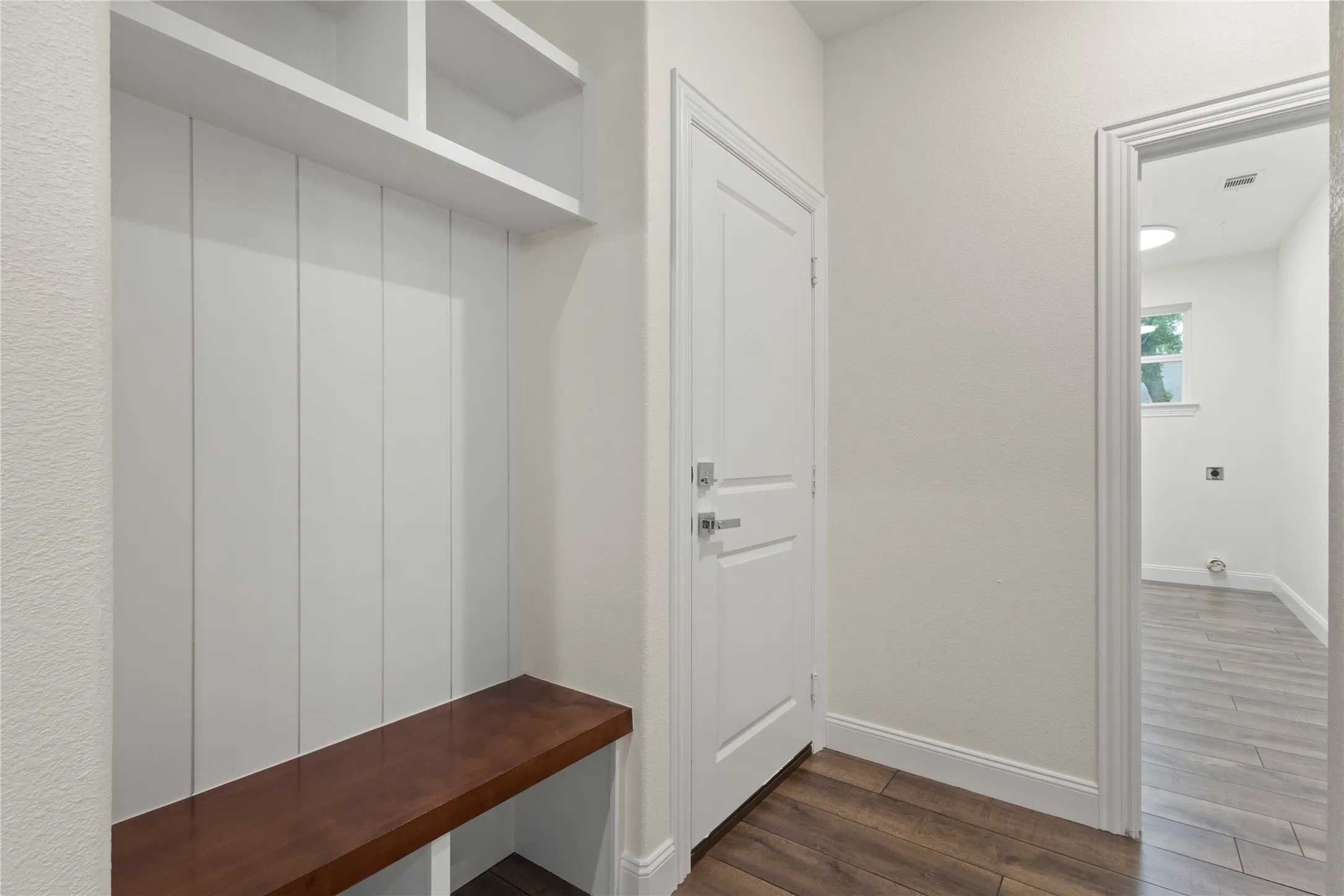 Built-in drop zone with a wood-finish bench and overhead storage cubbies