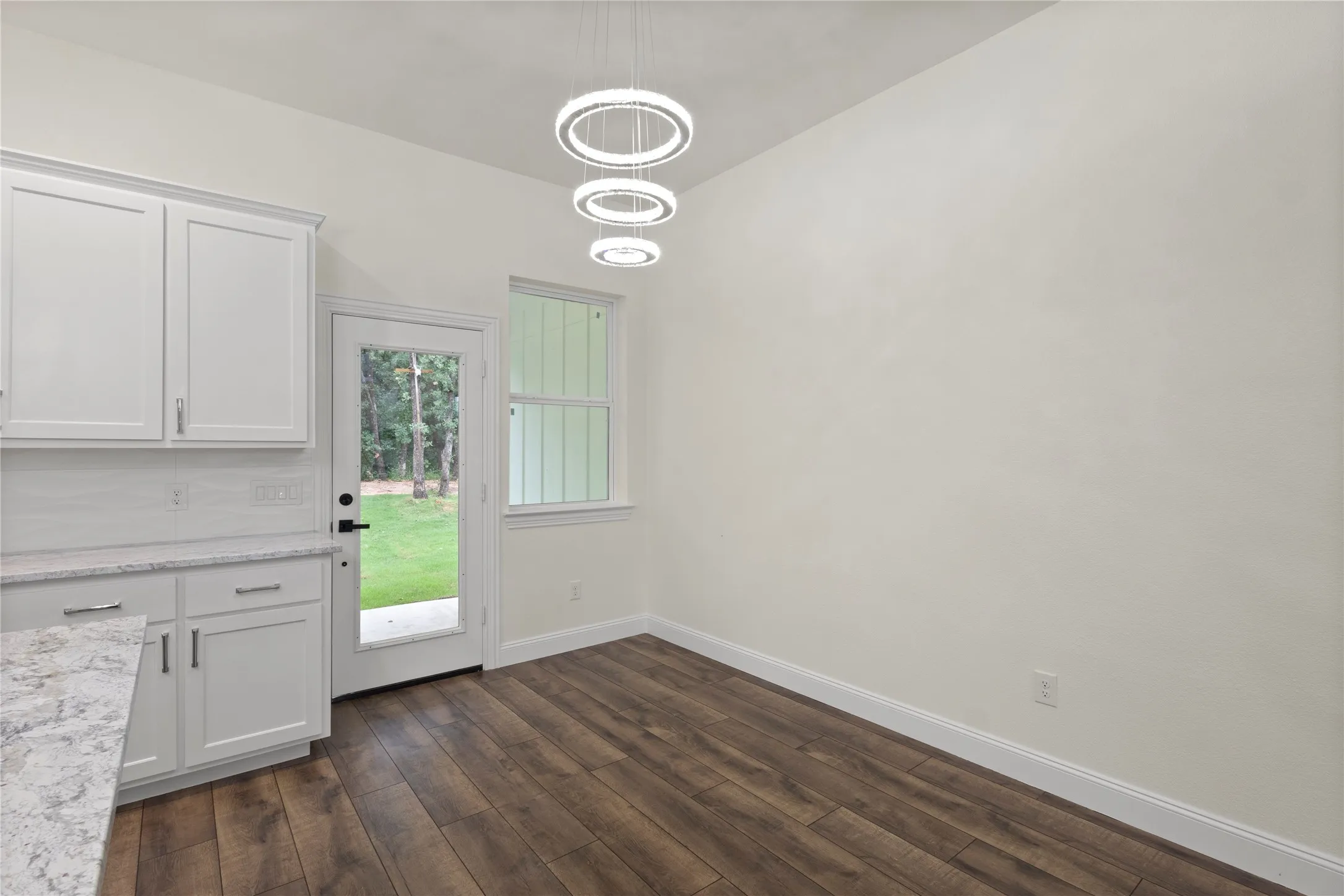Kitchen dining area featuring wood-finish flooring and a contemporary tiered chandelier