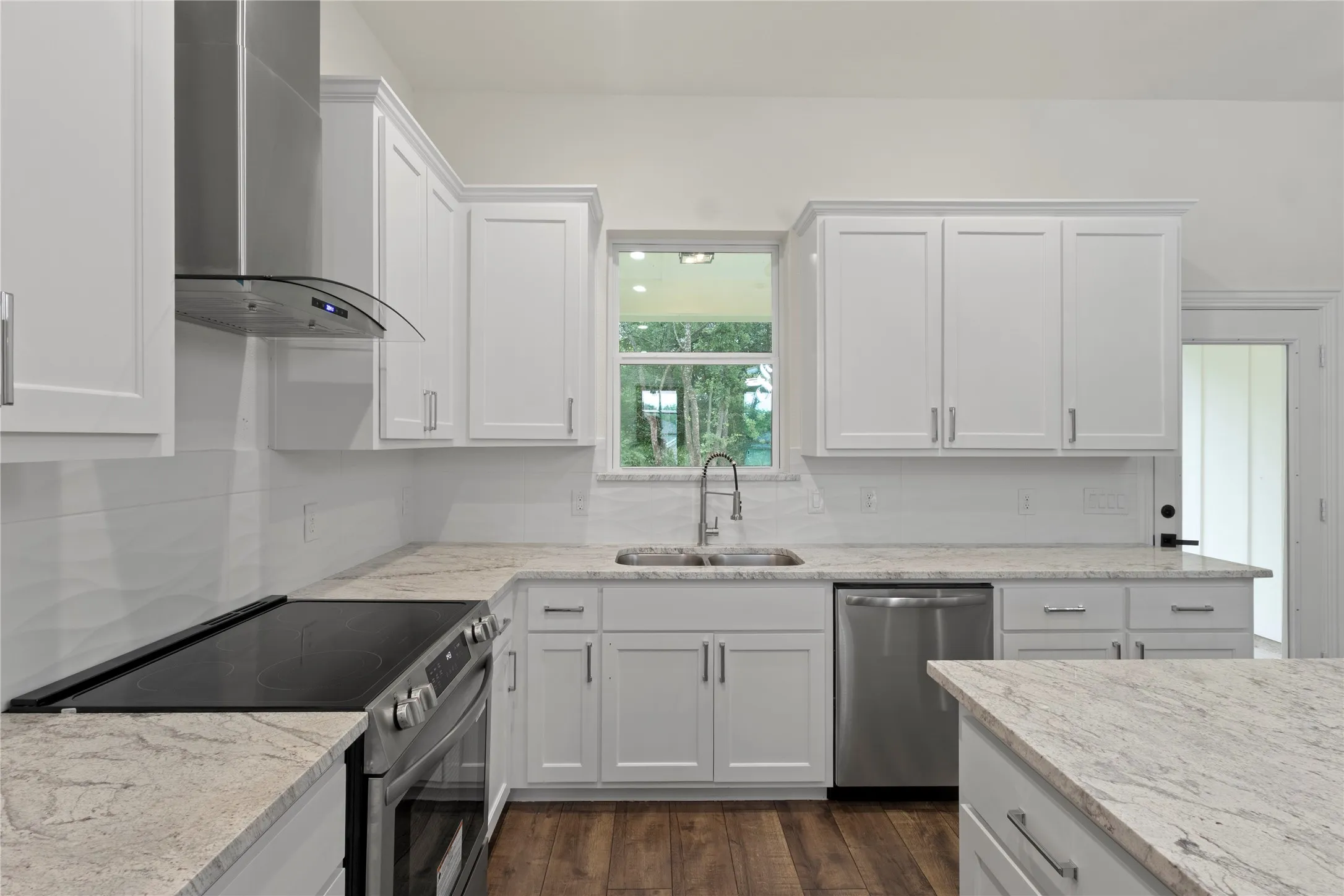 Contemporary kitchen featuring white shaker cabinetry, stainless steel appliances, light-toned countertops, a full subway tile backsplash, and wood-finish flooring