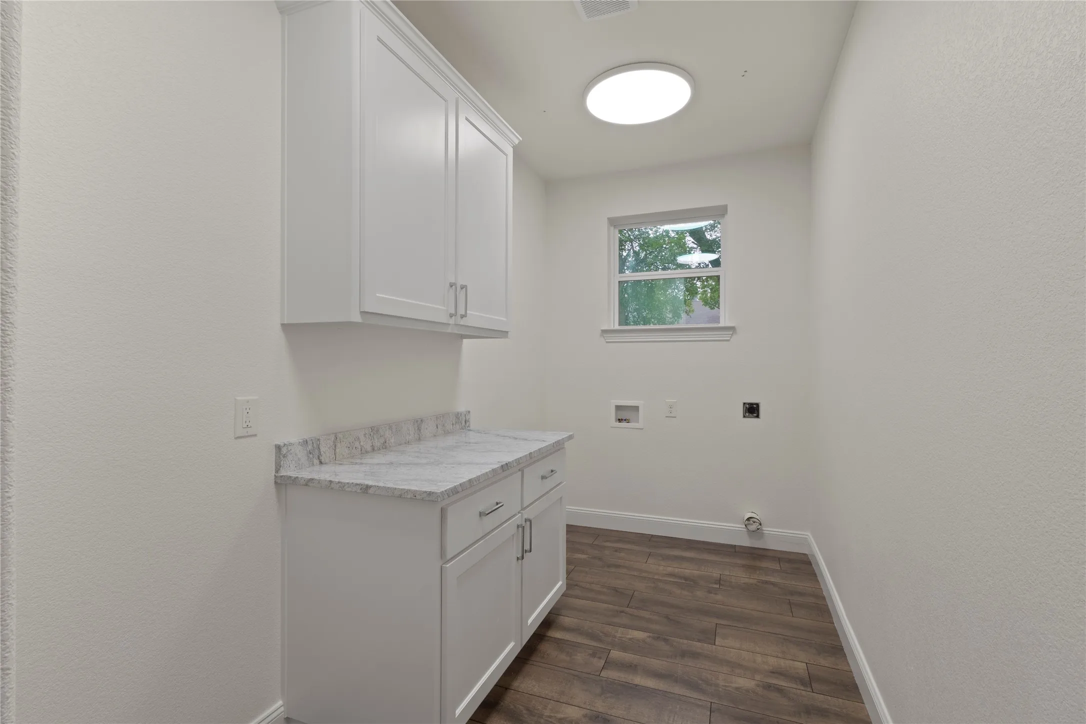 Utility space featuring white shaker cabinetry, a light-toned countertop, and wood-finish flooring