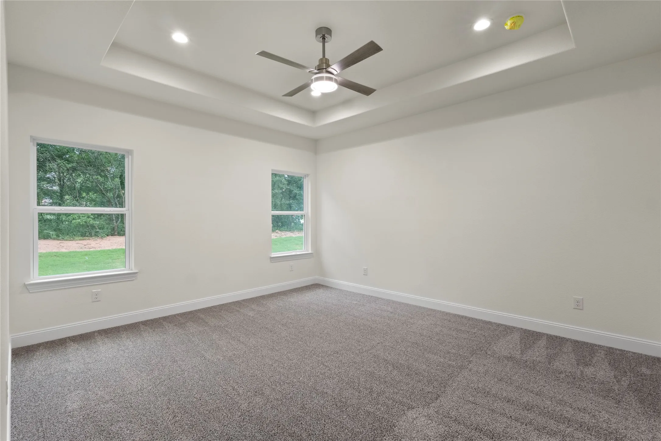 Spacious room featuring a tray ceiling, recessed lighting, and a contemporary ceiling fan