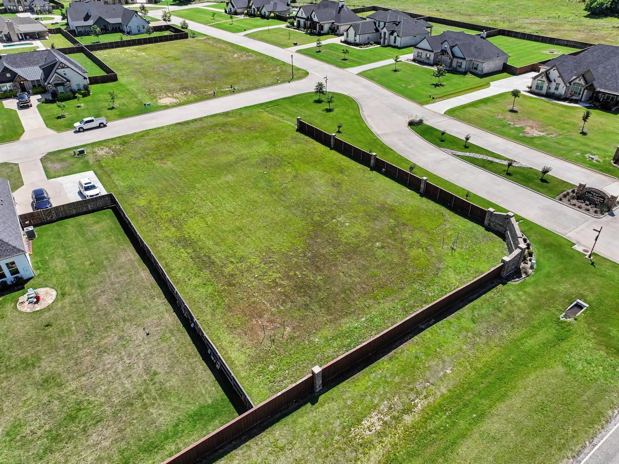 Expansive corner lot featuring a partial wood privacy fence with stone pillars, level topography, and green space