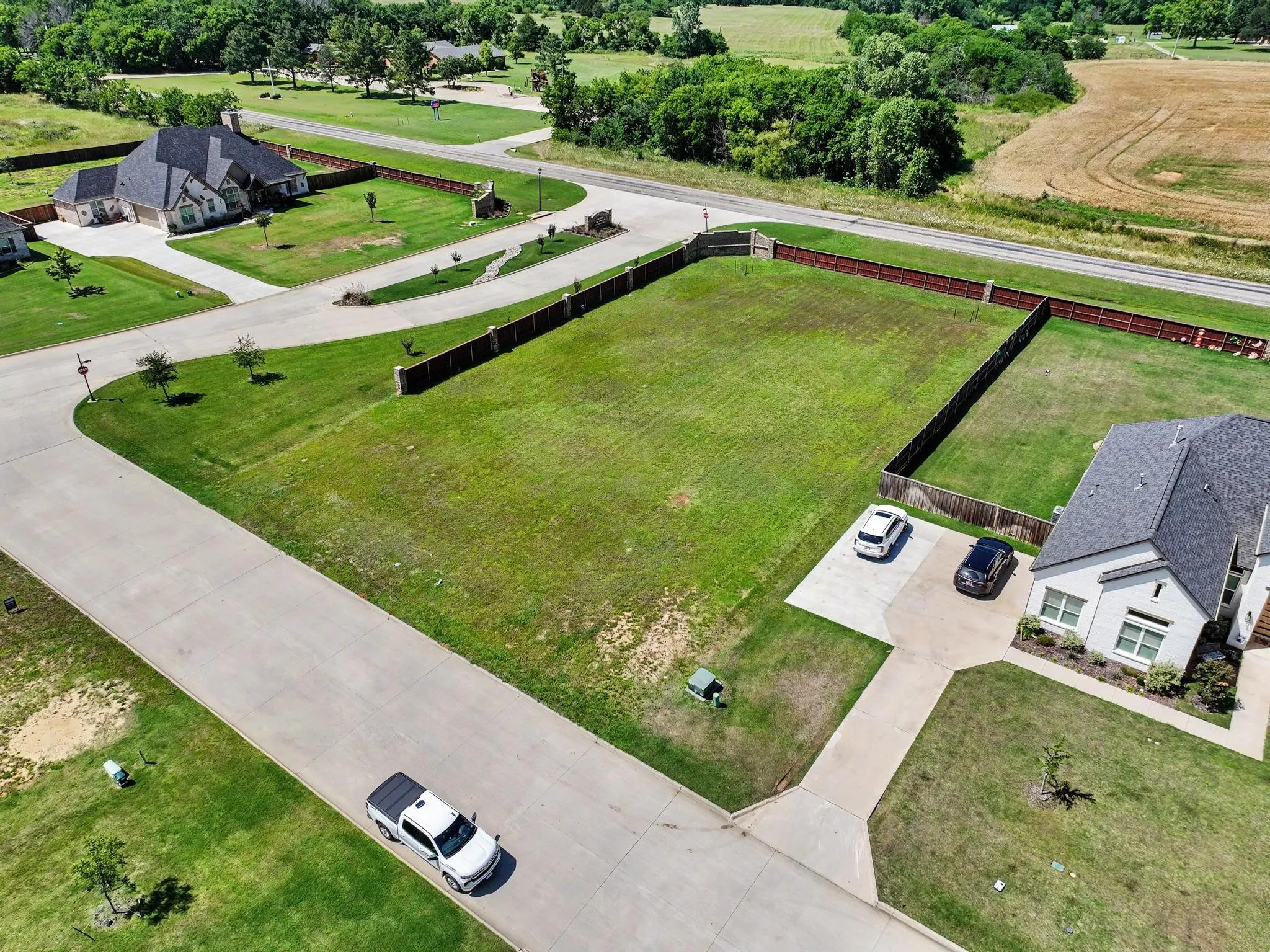 Expansive cleared lot featuring level terrain, a partial privacy fence, and paved road frontage