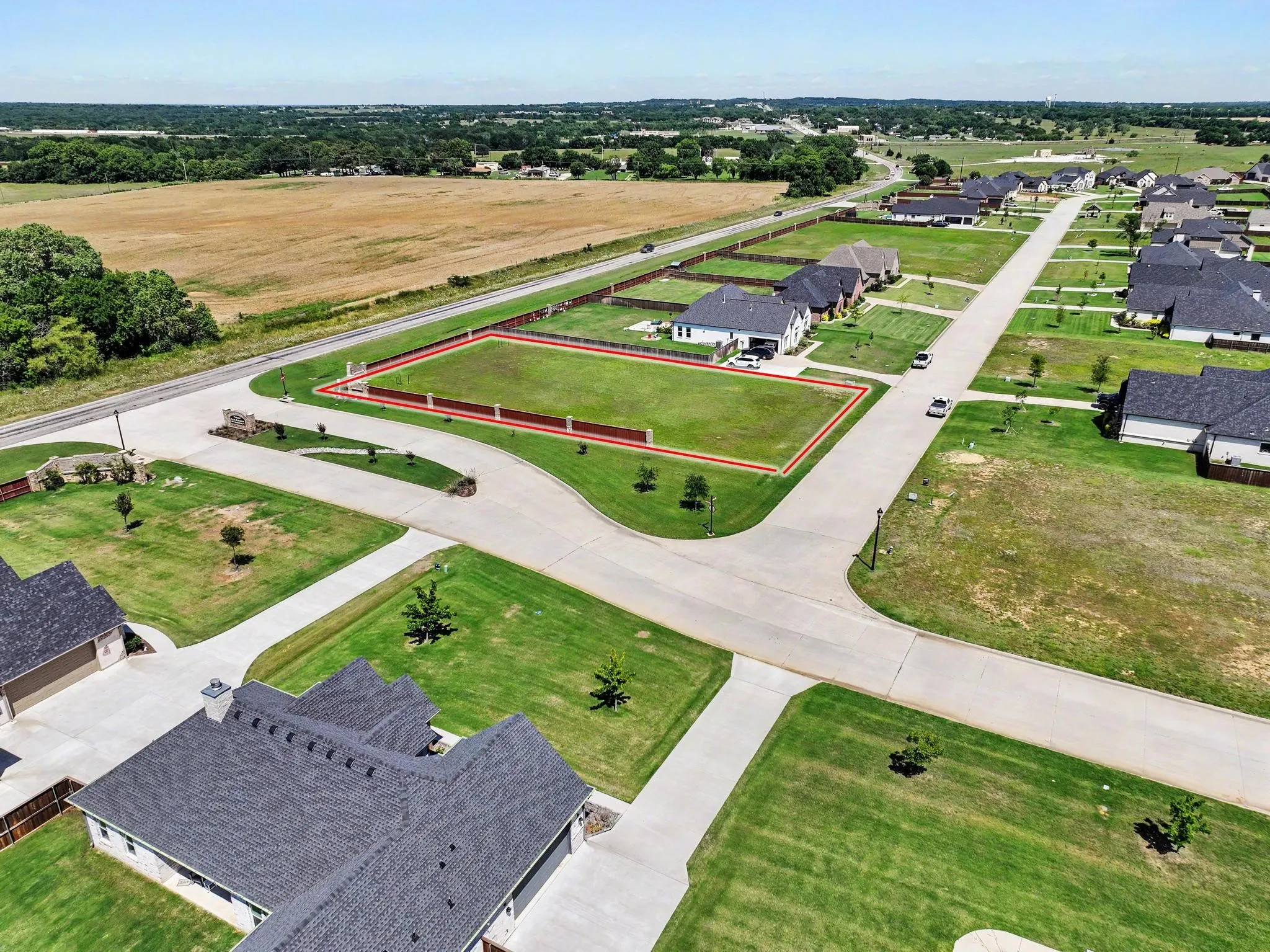 Grassed corner lot featuring a red-lined perimeter and partial fencing