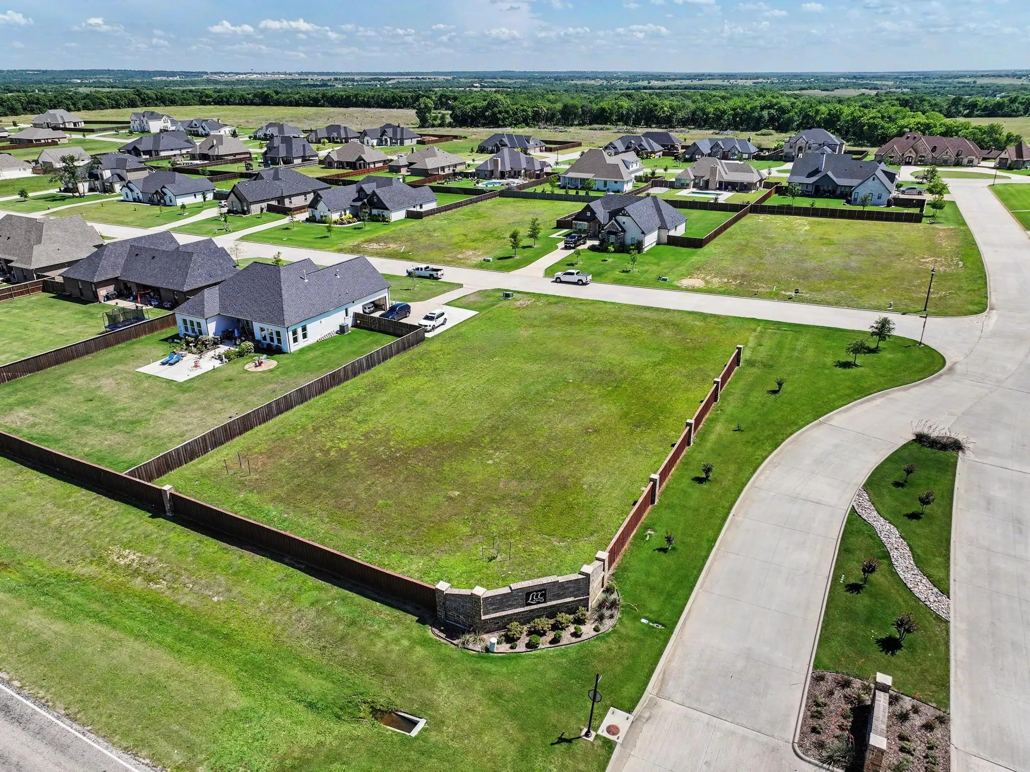 Expansive undeveloped lot featuring a stone and brick perimeter fence