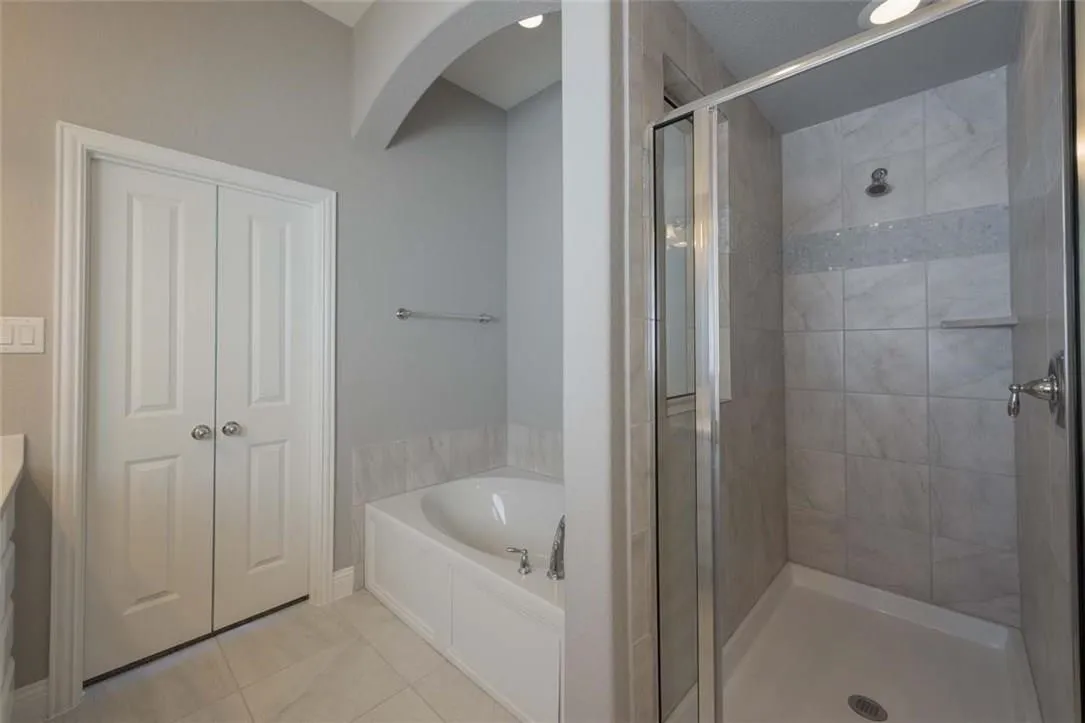 Bathroom featuring a built-in soaking tub, tiled shower with glass enclosure, and light gray wall paint